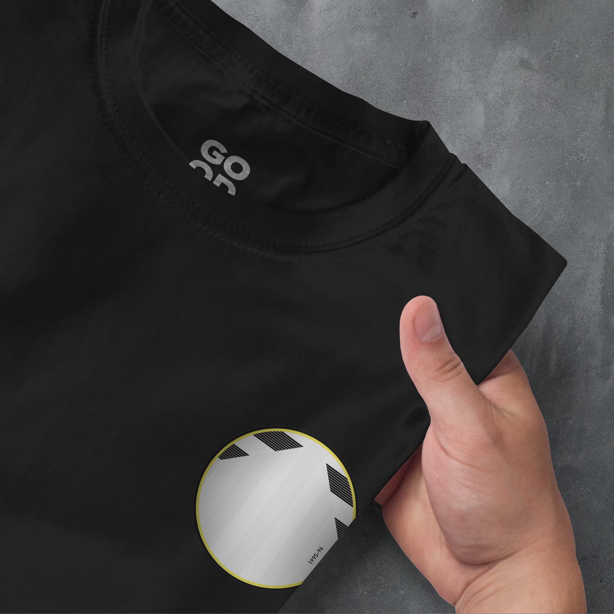 a hand pointing at a black shirt with a yellow circle on it