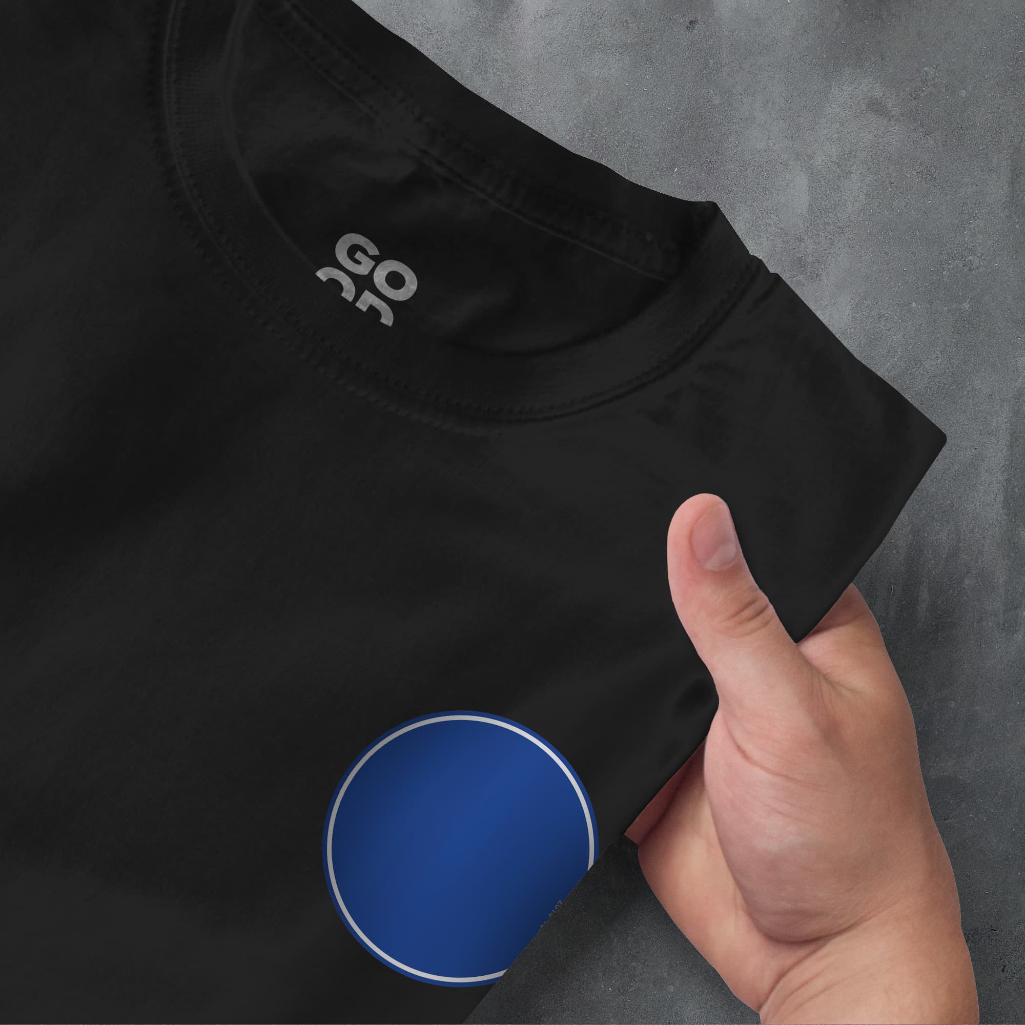 a hand pointing at a black shirt with a blue circle on it