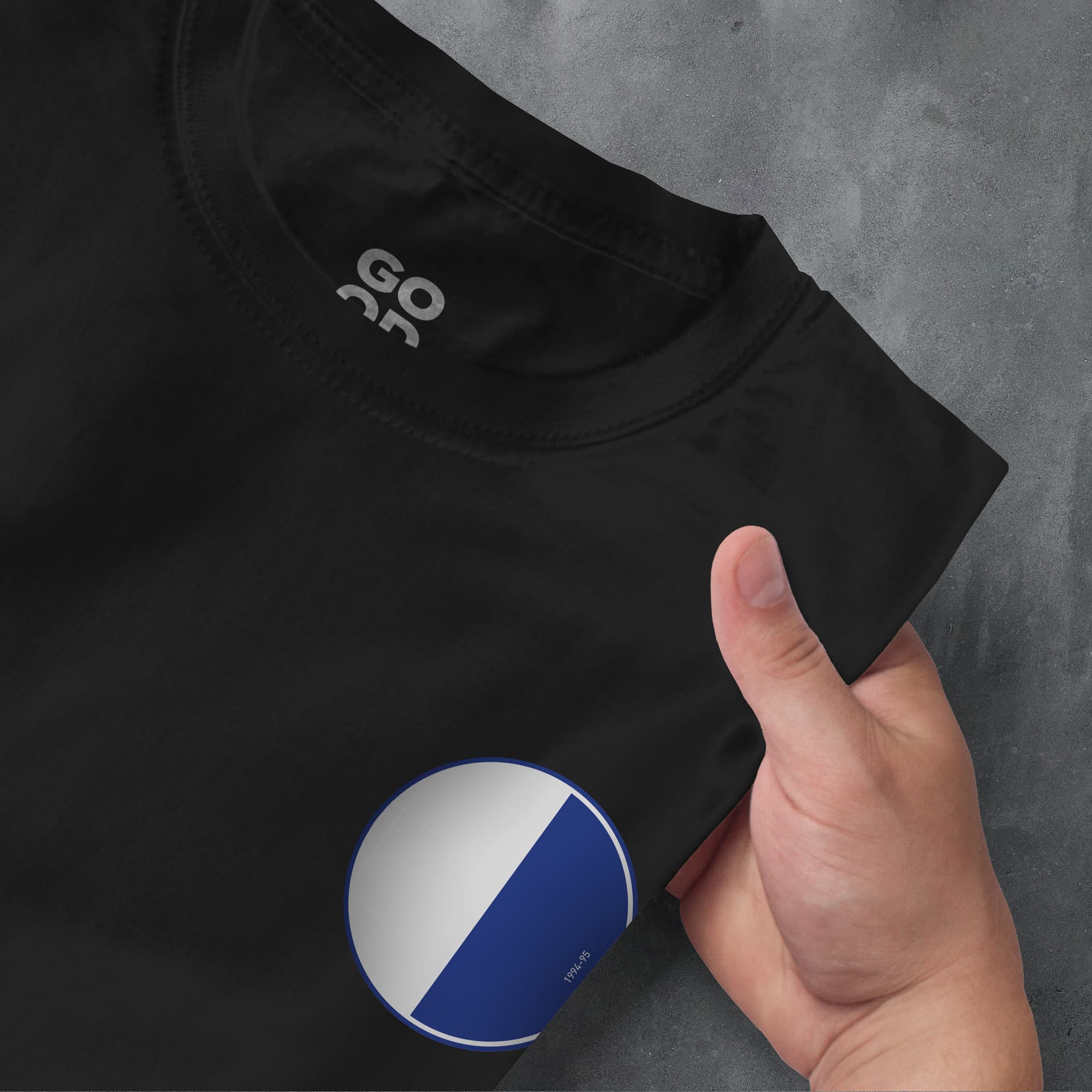a hand pointing at a black shirt with a blue and white circle on it