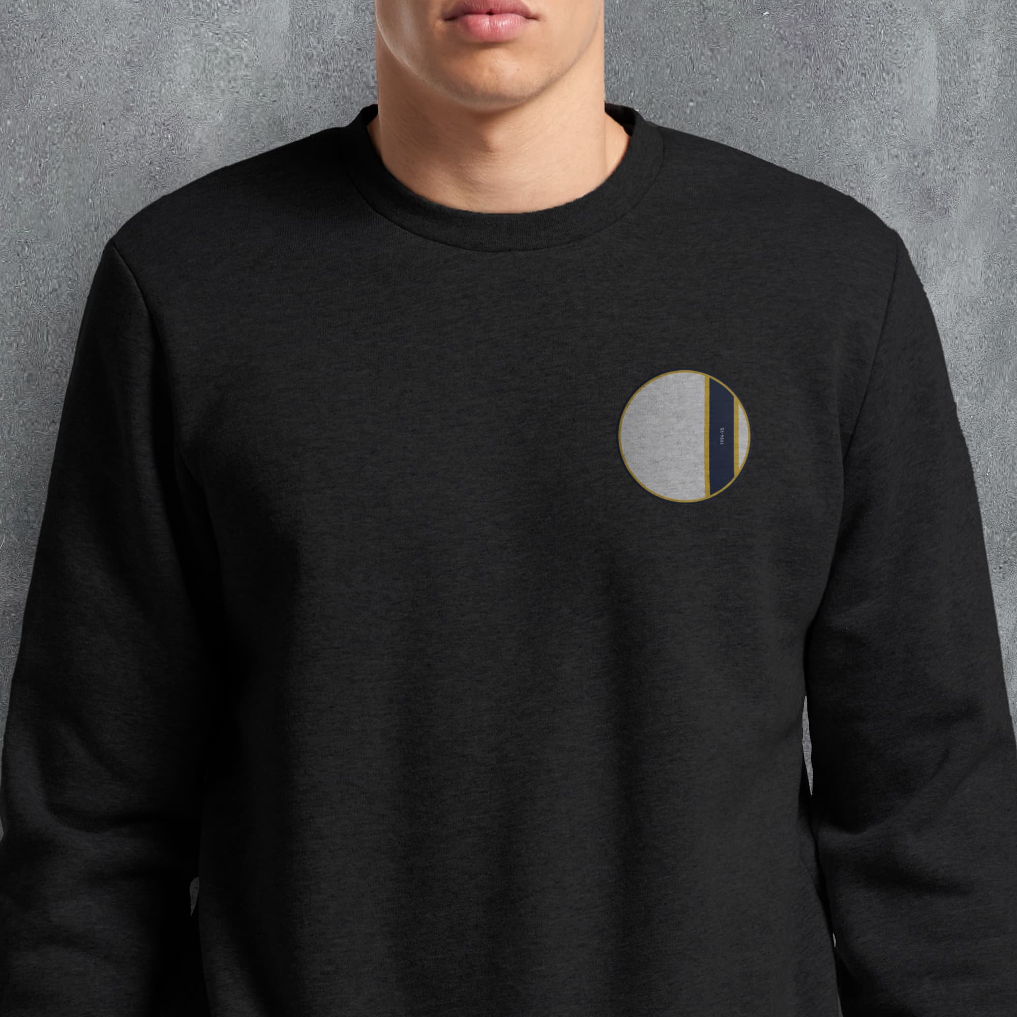 a man wearing a black sweatshirt with a gold logo