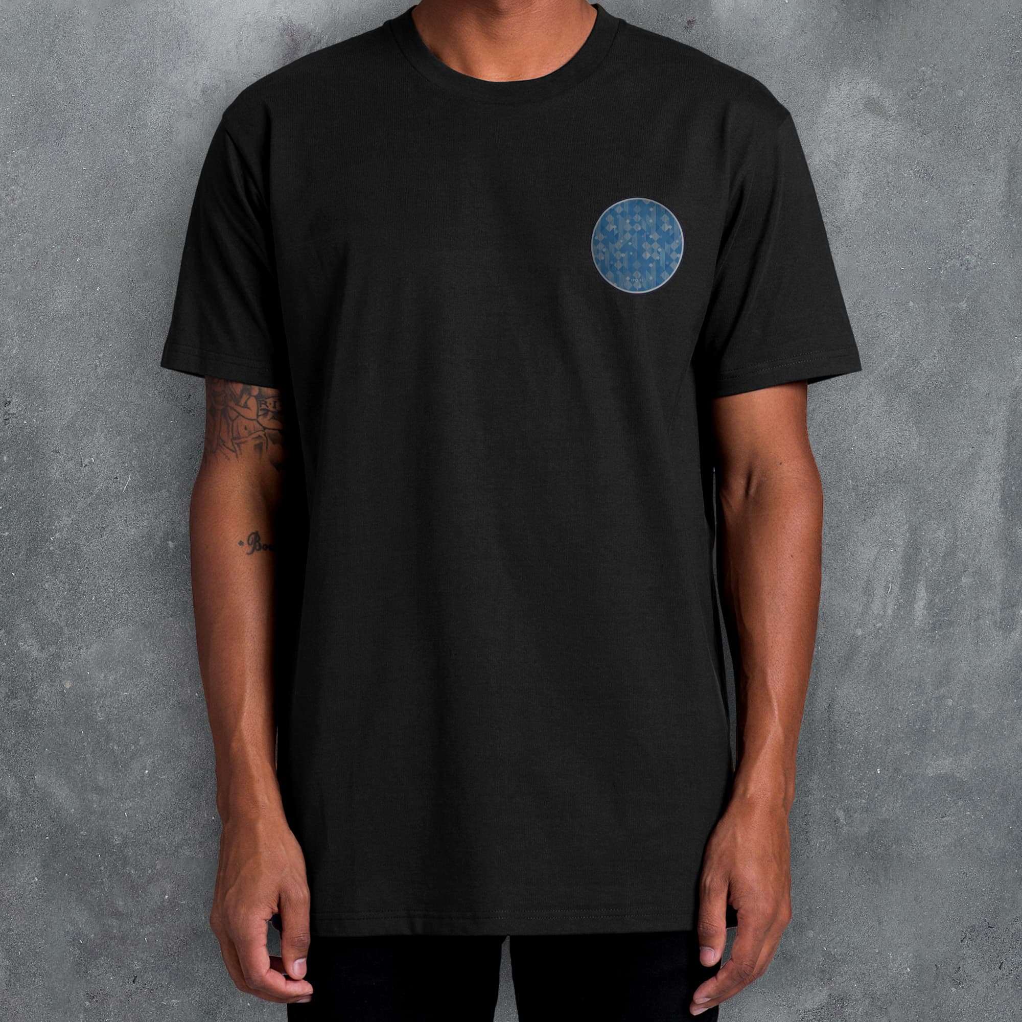 a man standing in front of a wall wearing a black shirt with a blue circle