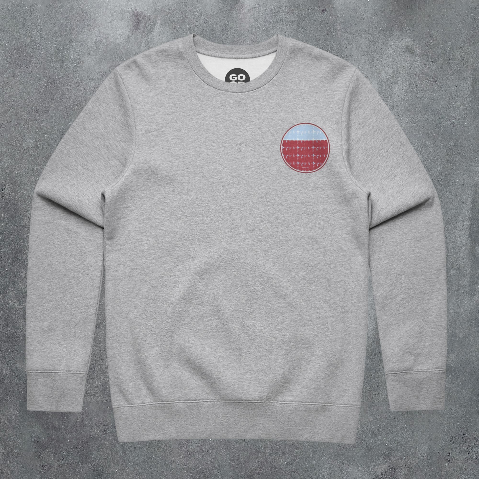 a grey sweatshirt with a red and blue patch on the chest