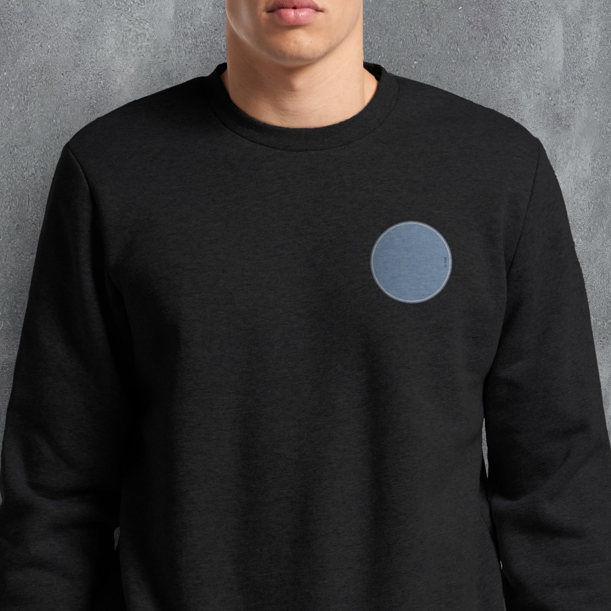 a man wearing a black sweatshirt with a blue circle on it