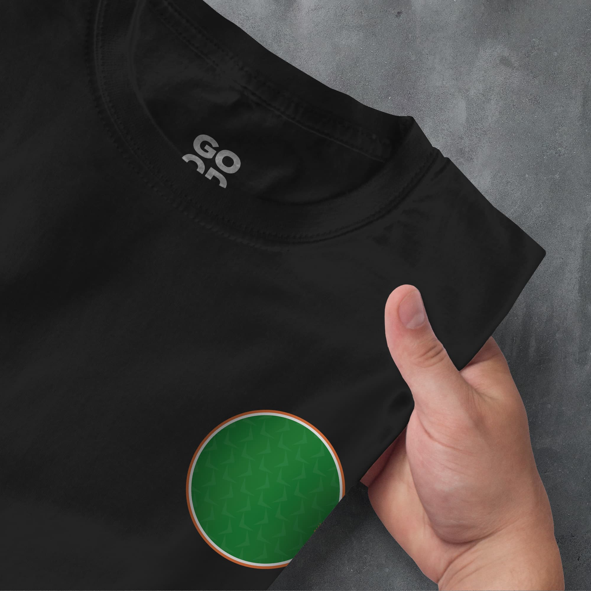 a person's hand pointing at a black t - shirt with a green circle