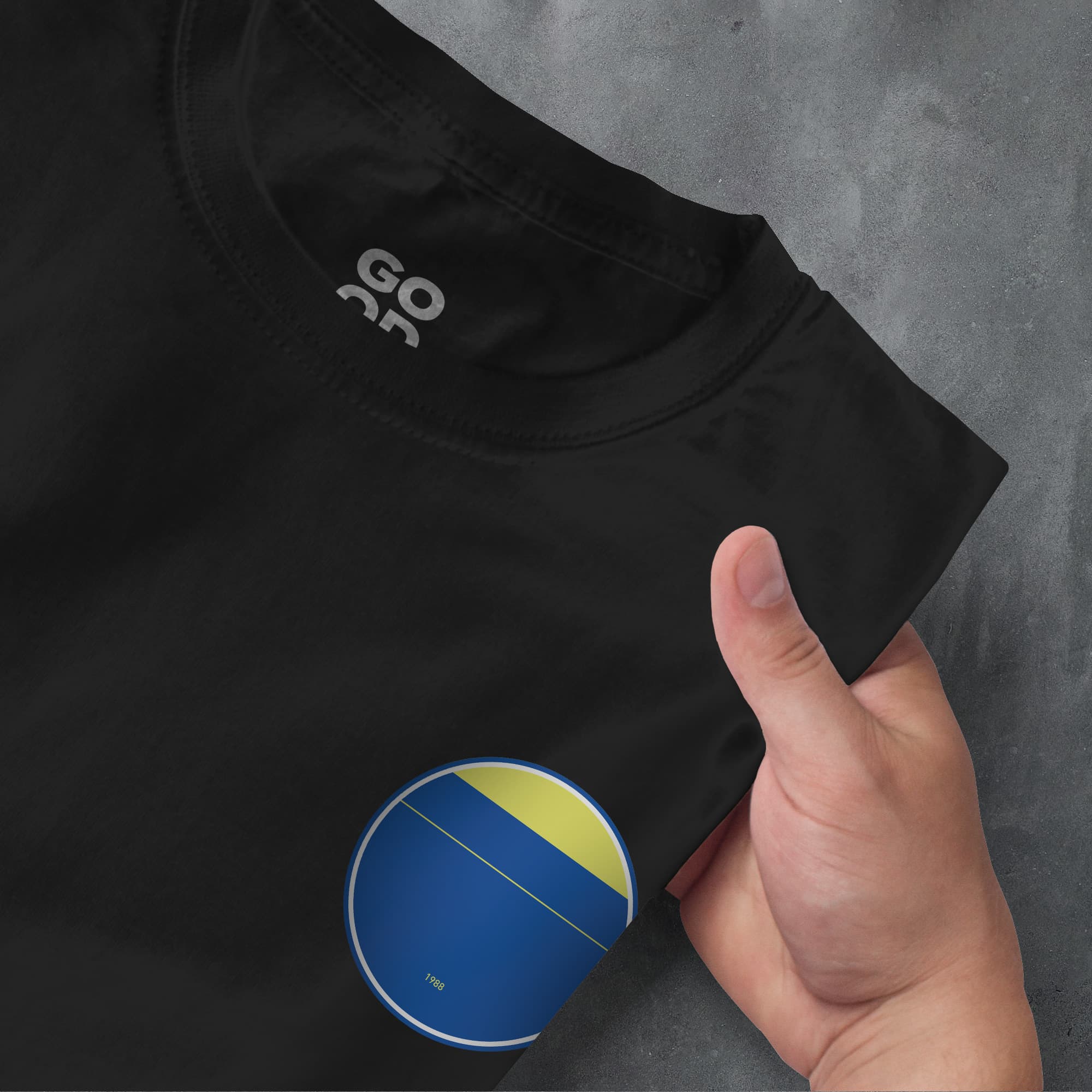 a hand pointing at a black shirt with a yellow and blue circle on it
