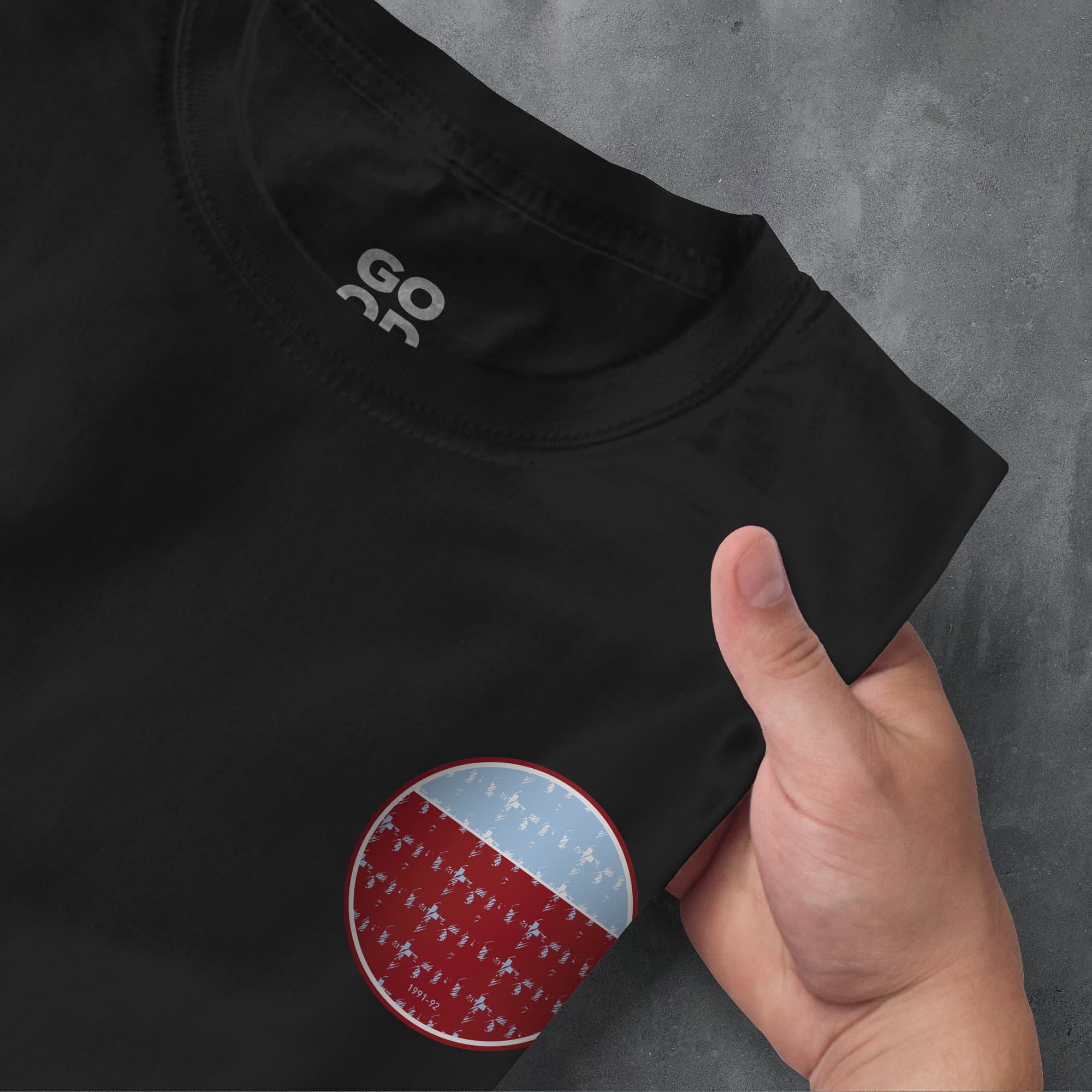 a person's hand holding a black shirt with a red and blue patch on