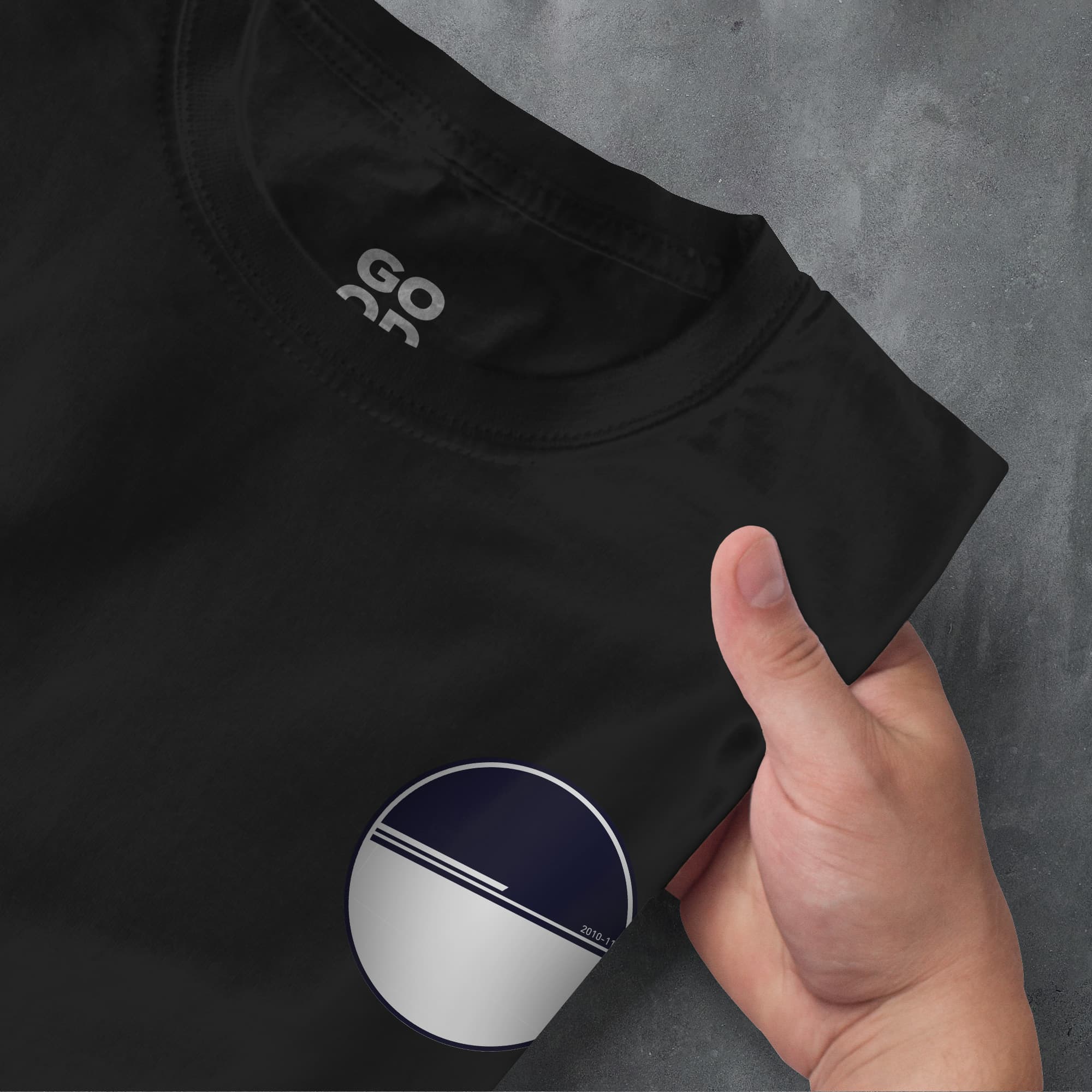 a person's hand pointing at a black t - shirt with a white and