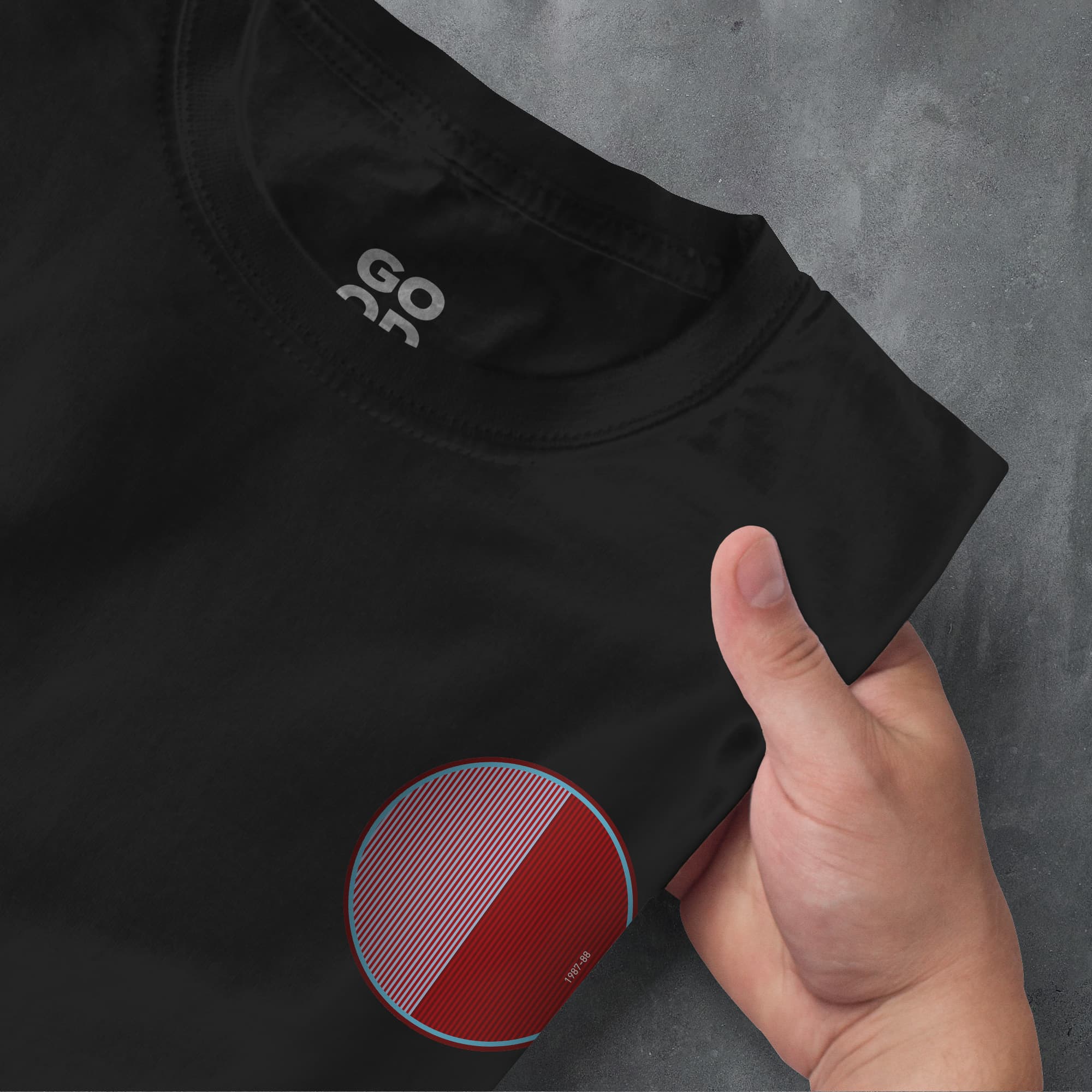 a person's hand pointing at a black shirt with a red circle on it