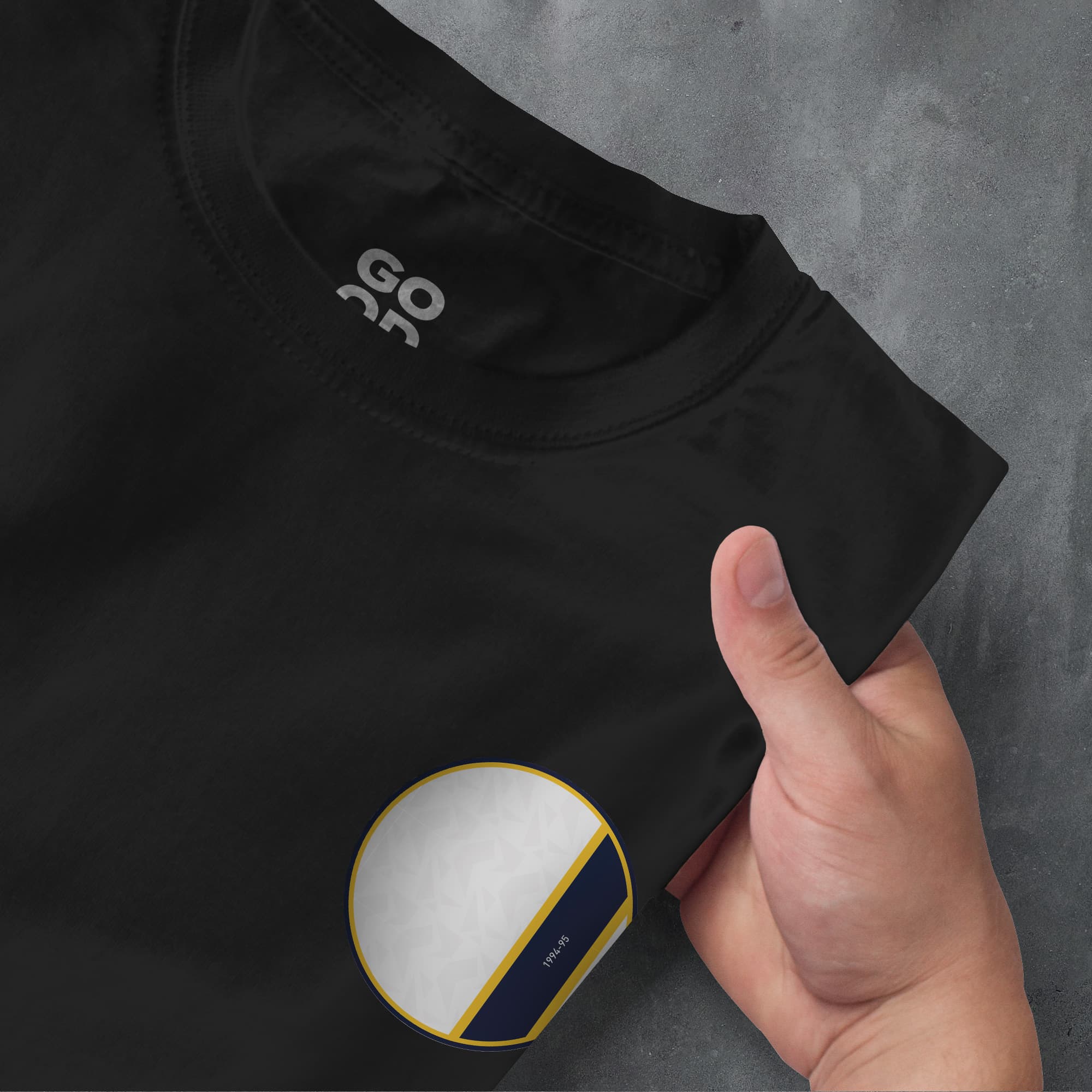 a hand pointing at a black shirt with a white and blue circle on it