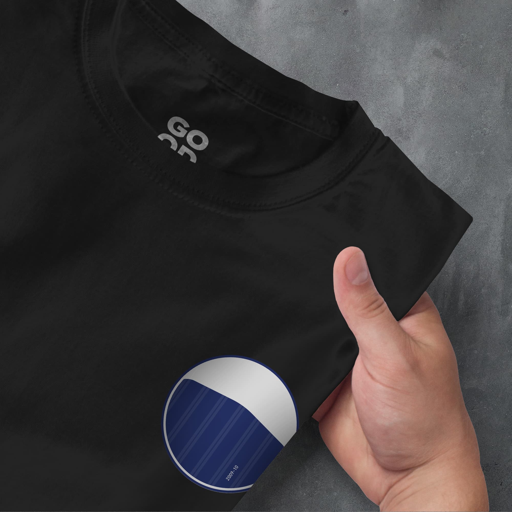 a person's hand pointing at a black t - shirt with a blue and