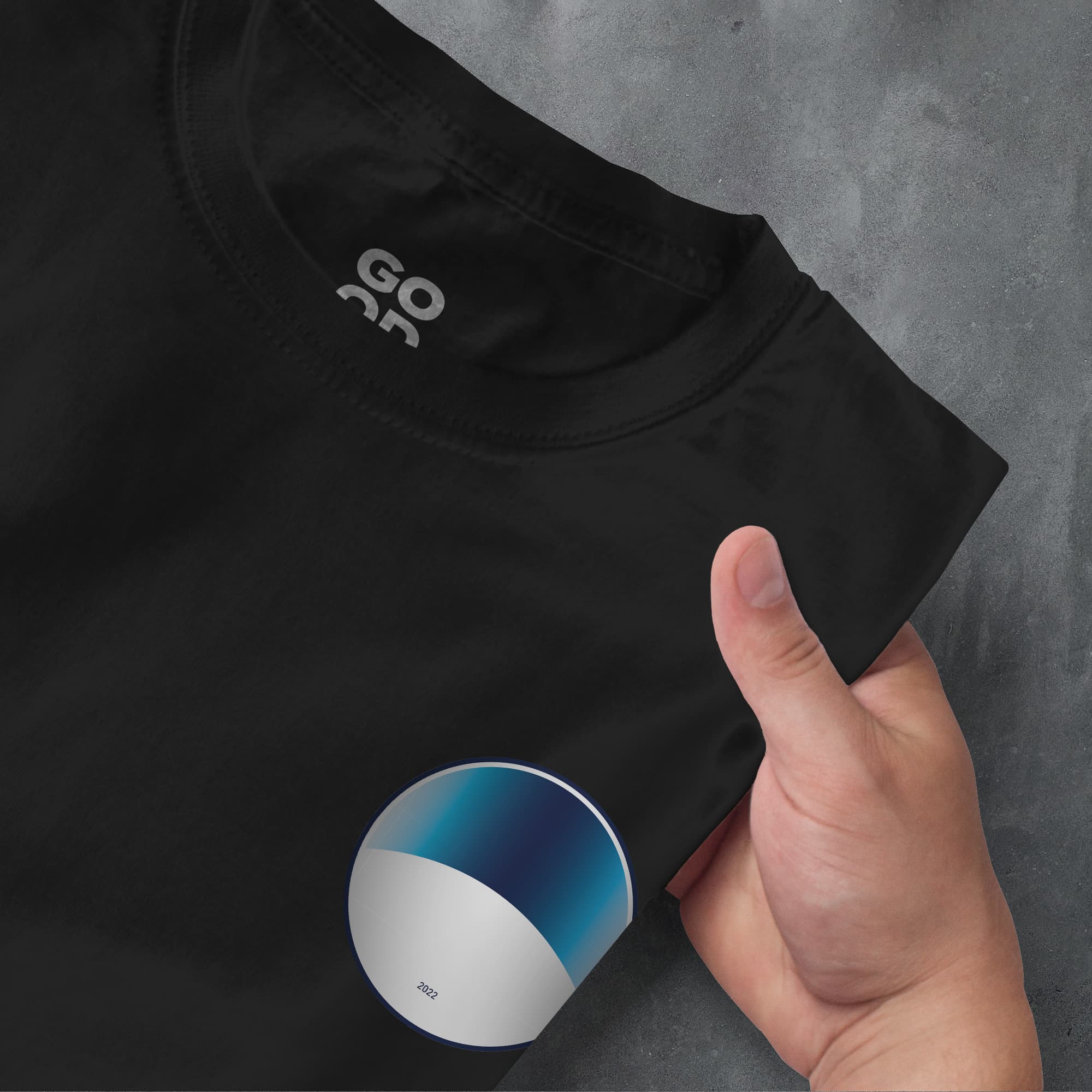 a hand pointing at a black shirt with a white and blue circle on it