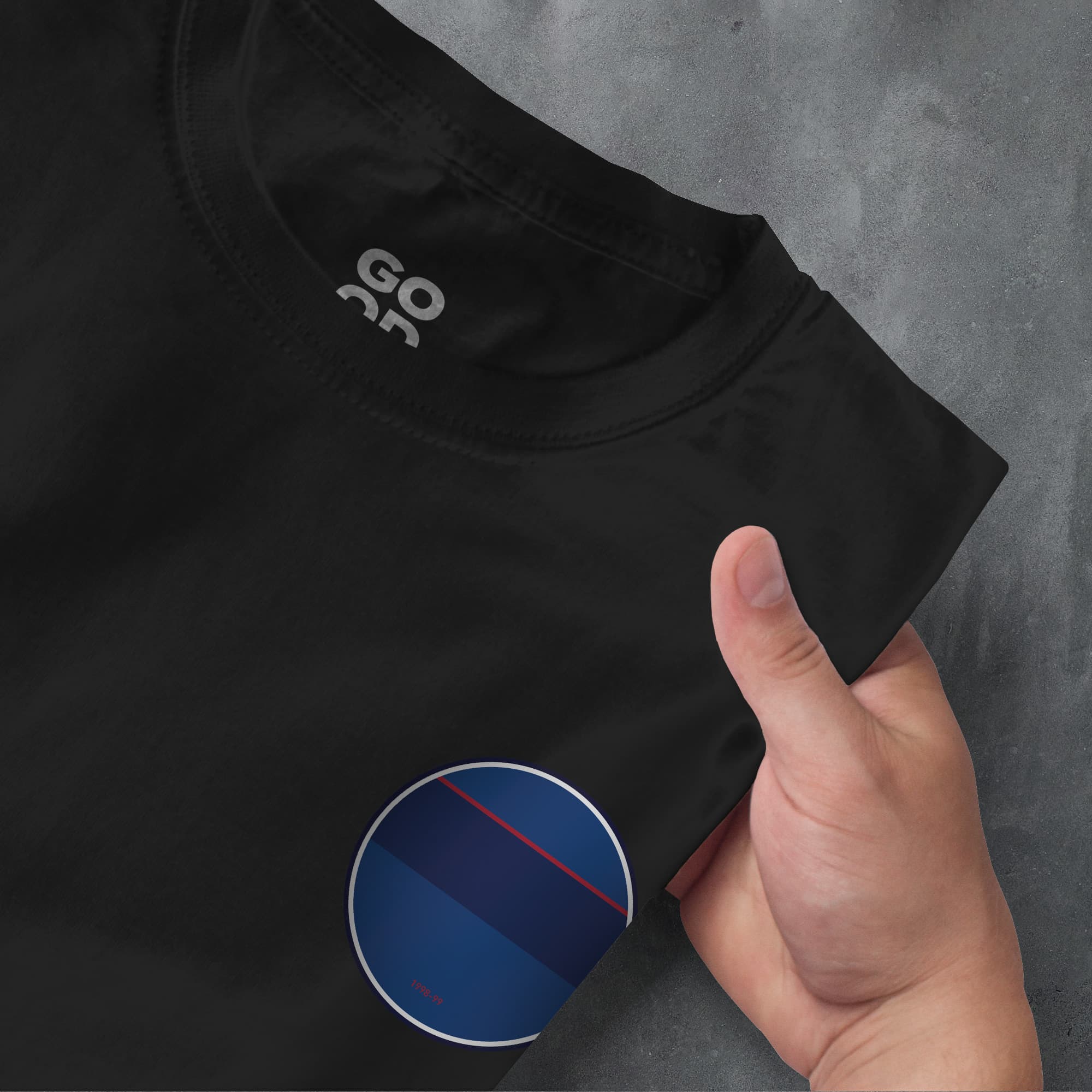 a hand pointing at a black shirt with a blue circle on it