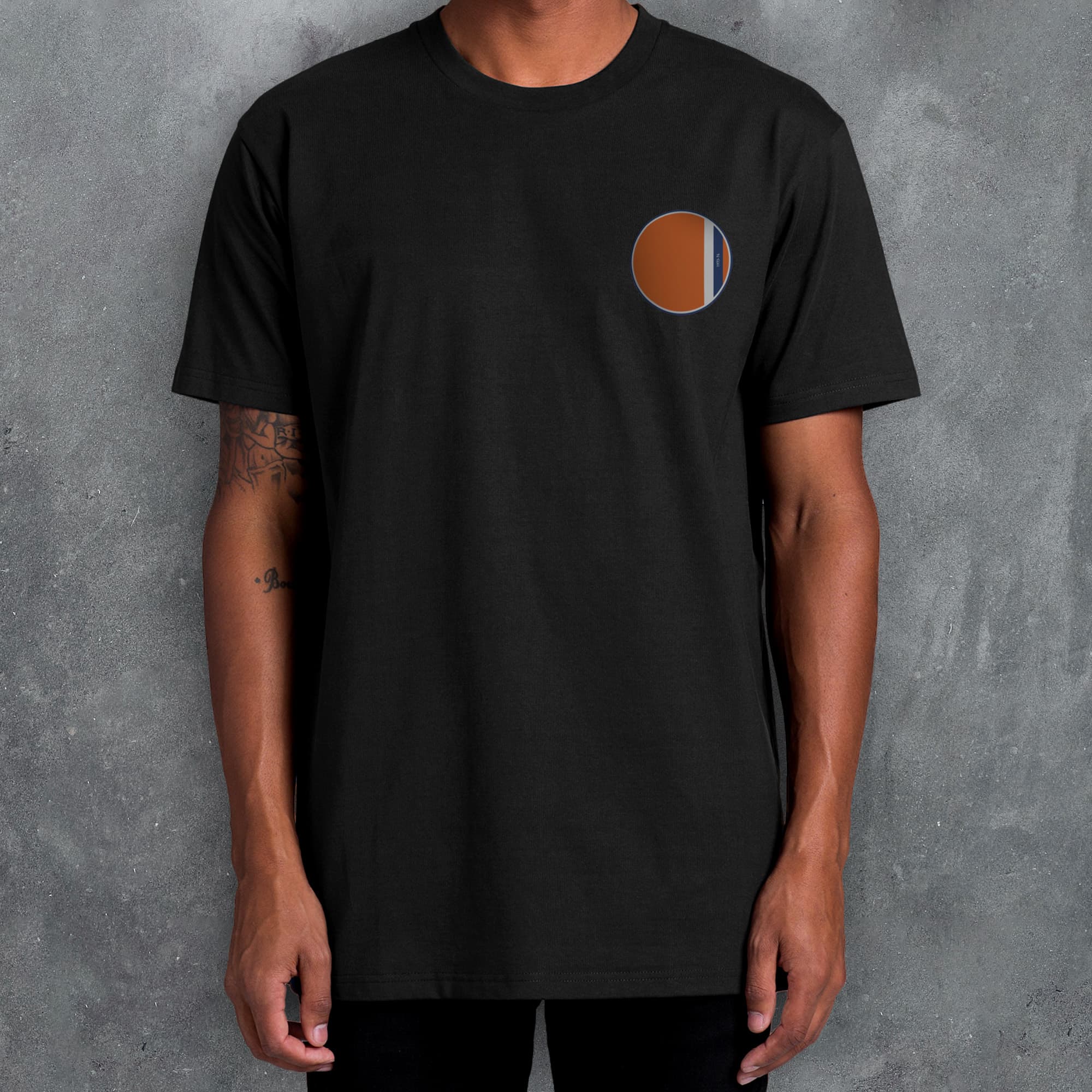 a man wearing a black t - shirt with an orange circle on it