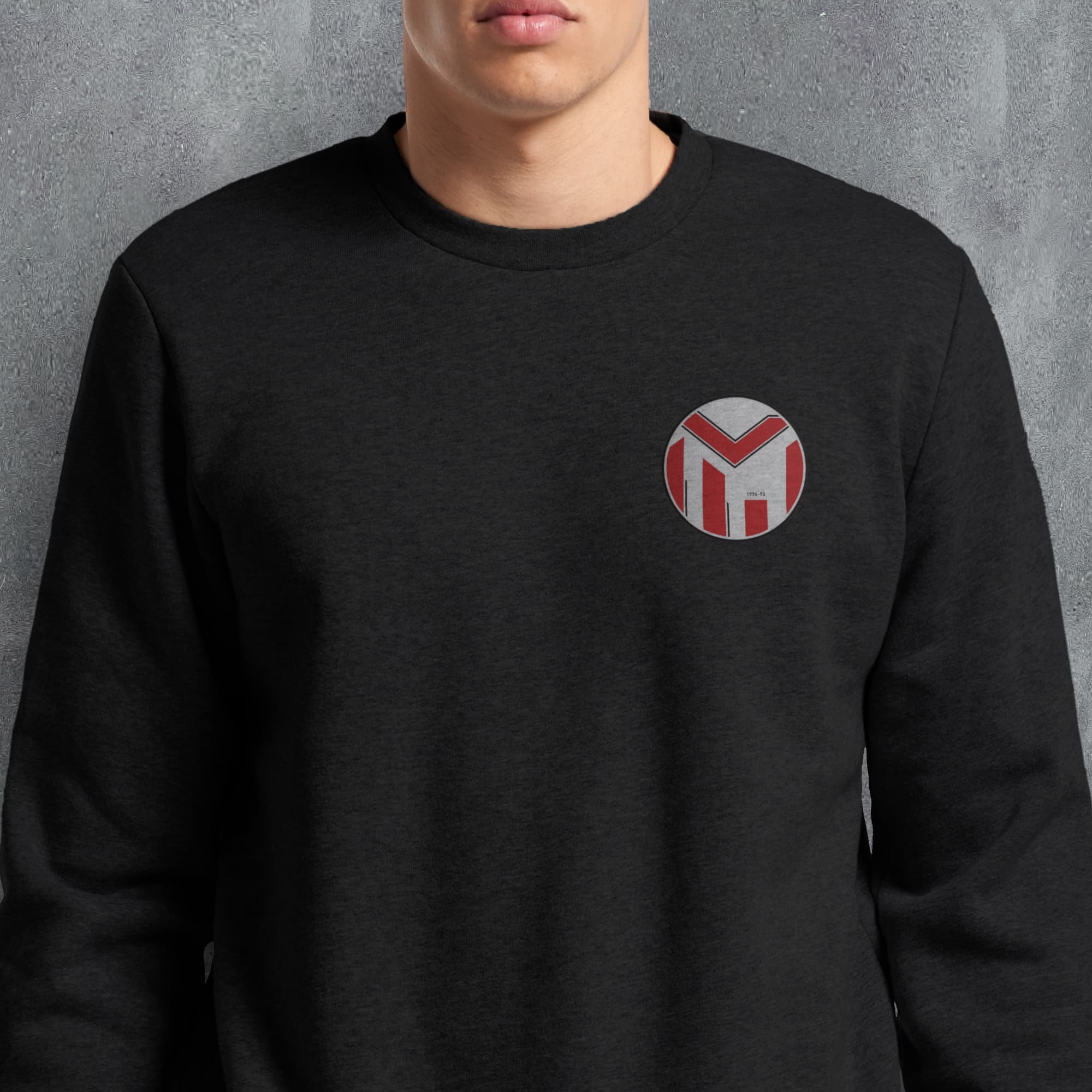 a man wearing a black sweatshirt with a red and white m on it
