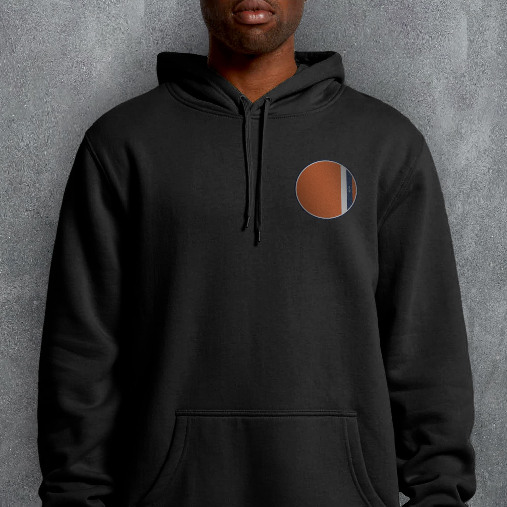 a man wearing a black hoodie with a brown circle on it
