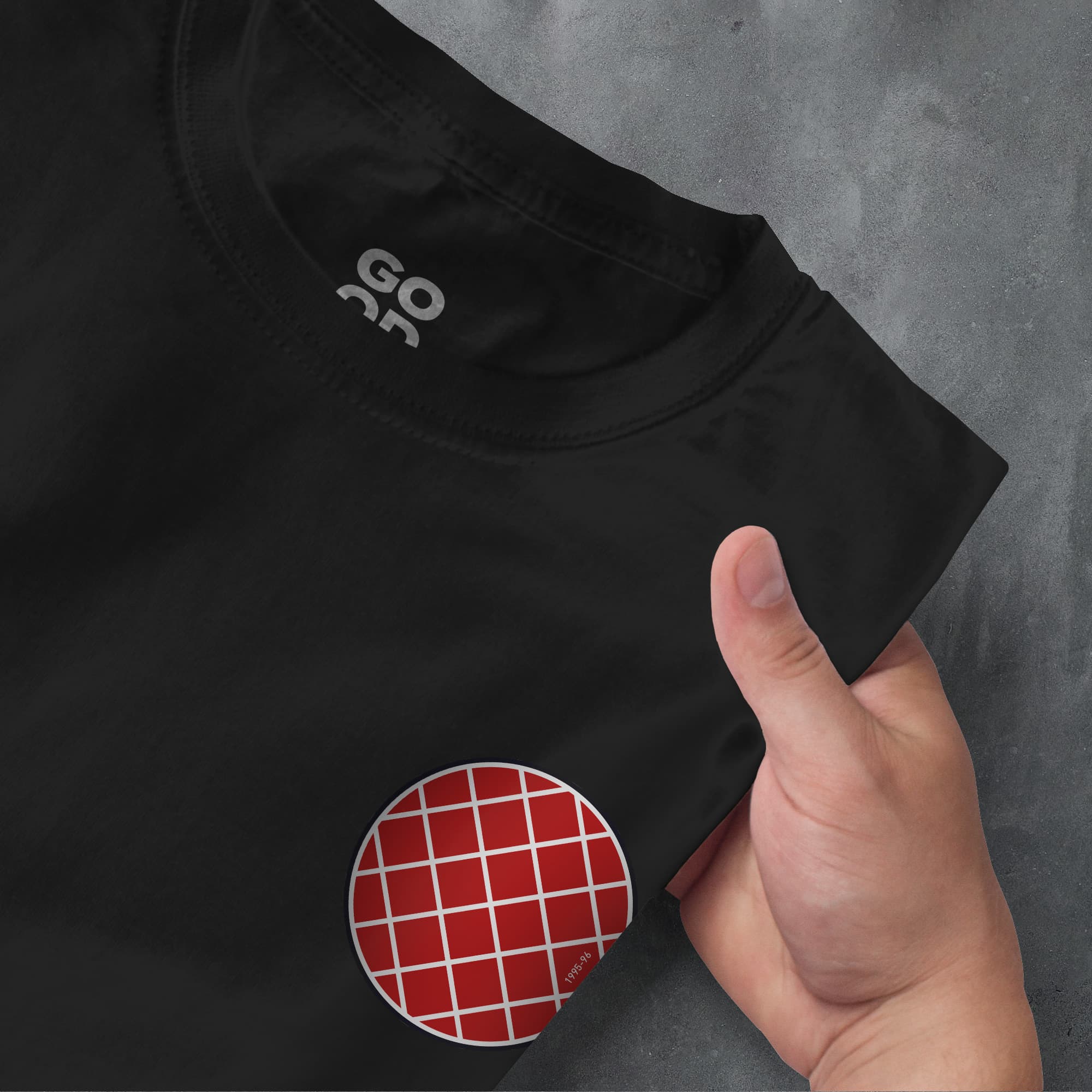 a hand pointing at a red and white checkered circle on a black shirt