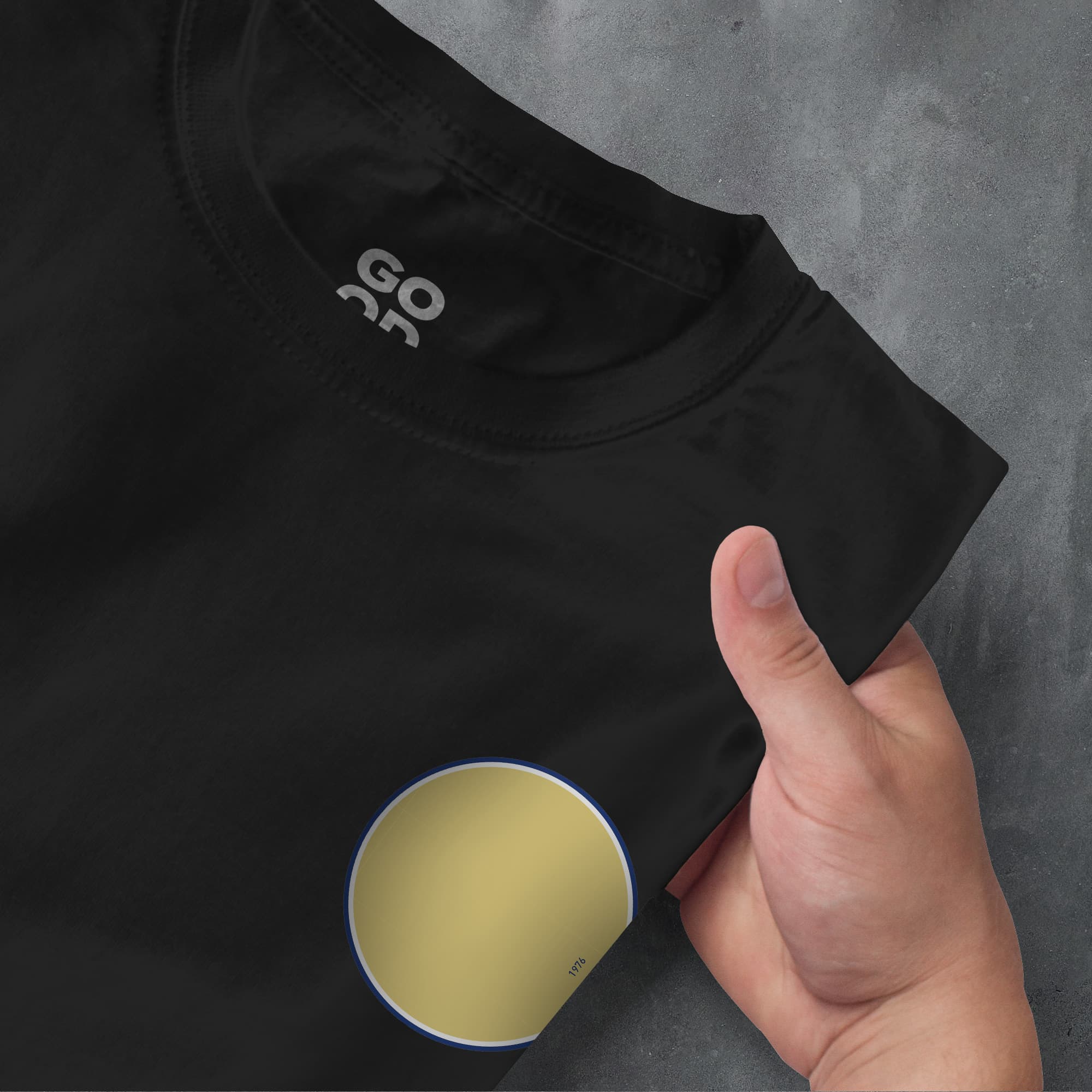 a person's hand pointing at a t - shirt with a yellow circle on