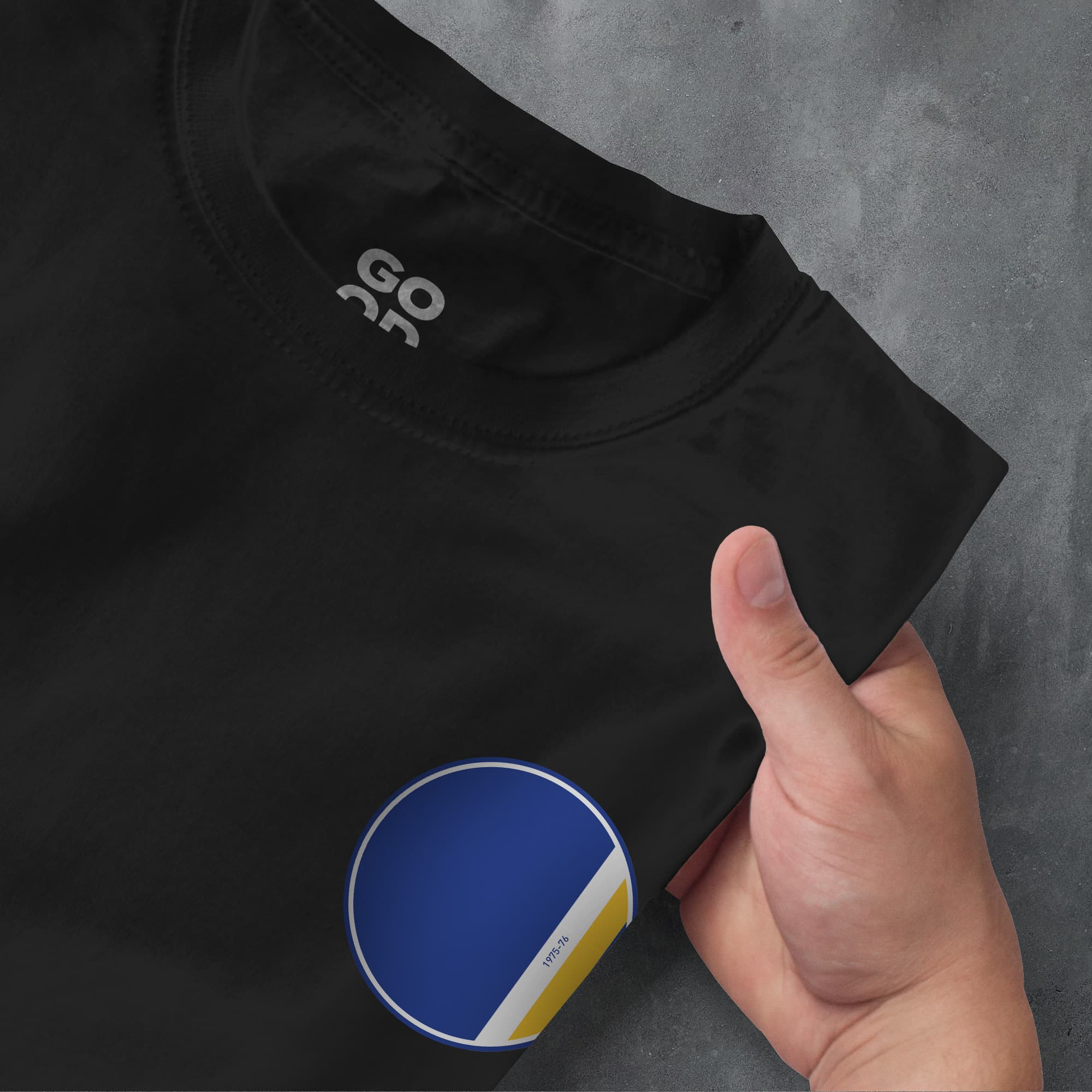 a hand pointing at a black shirt with a yellow and blue circle on it