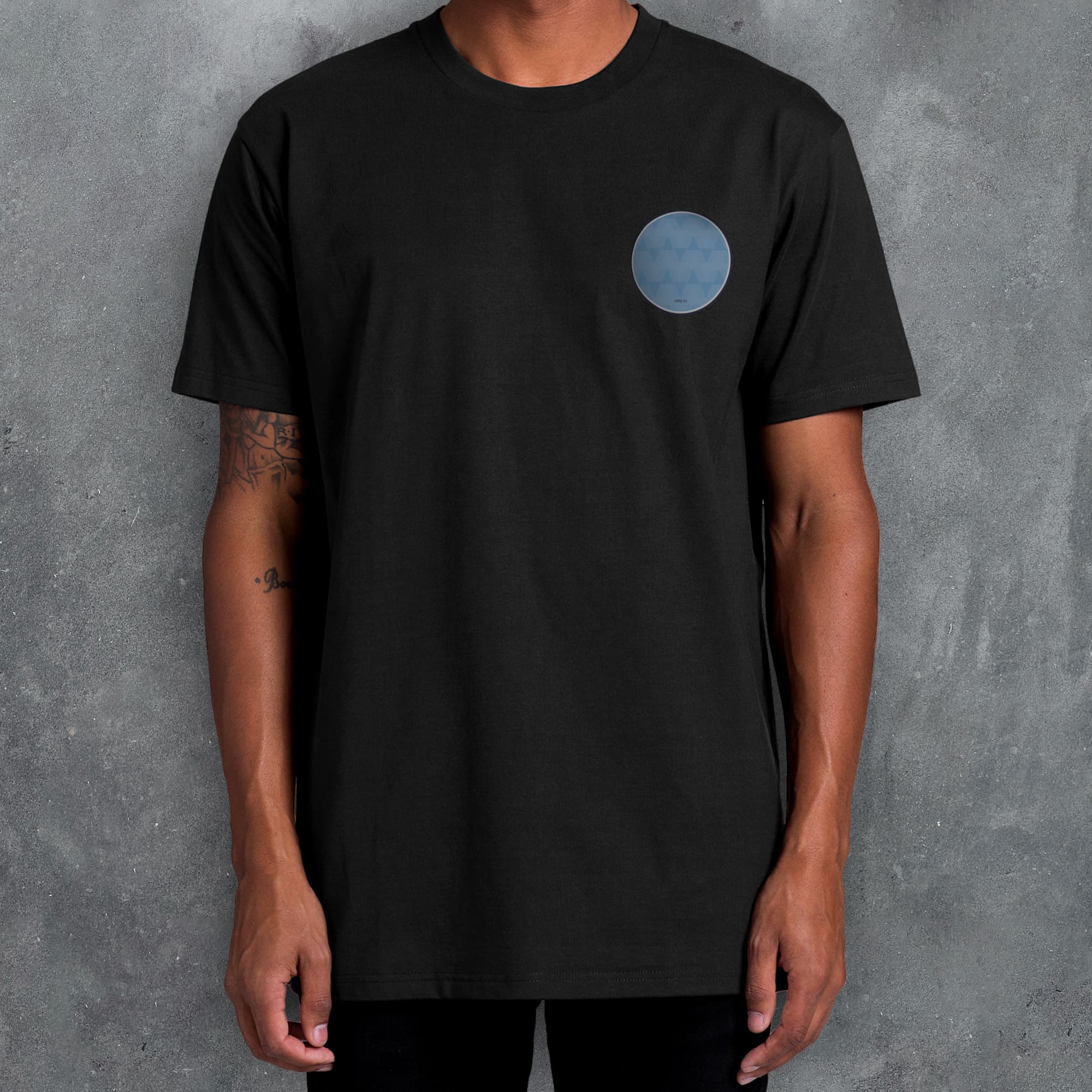 a man wearing a black t - shirt with a blue circle on it