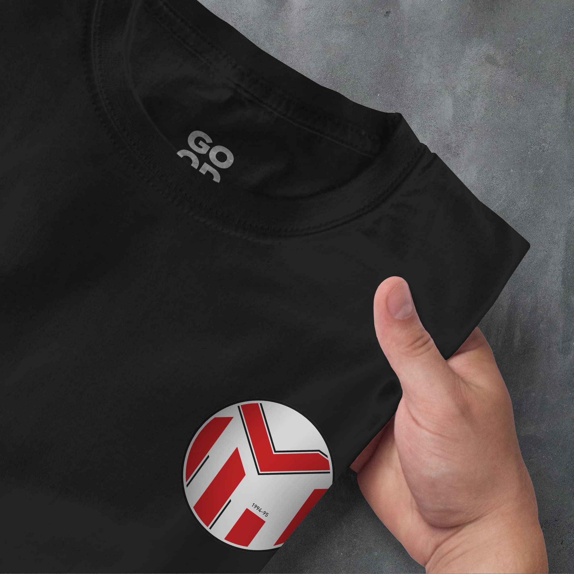 a hand pointing at a black shirt with a red and white logo