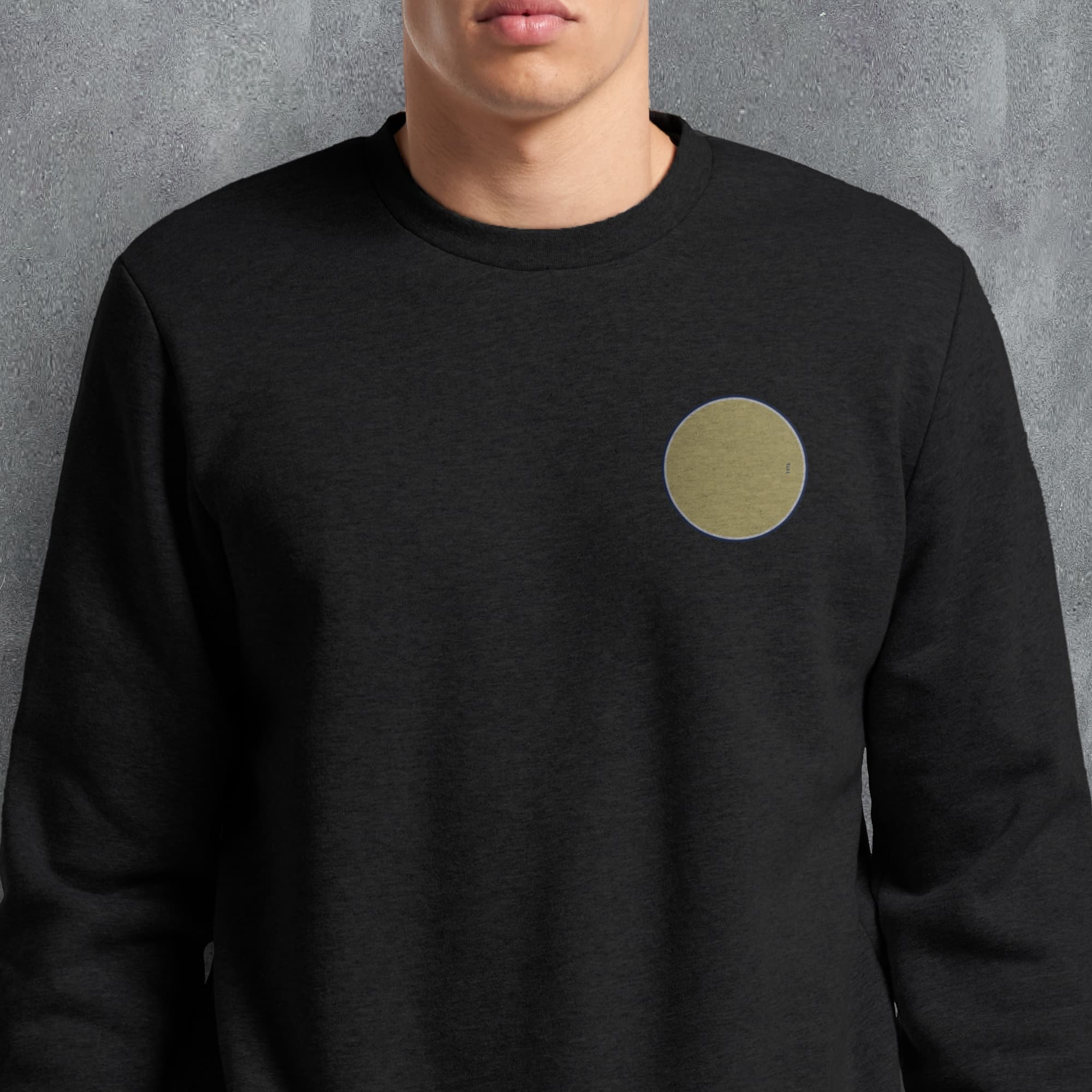 a man wearing a black sweatshirt with a gold circle on it