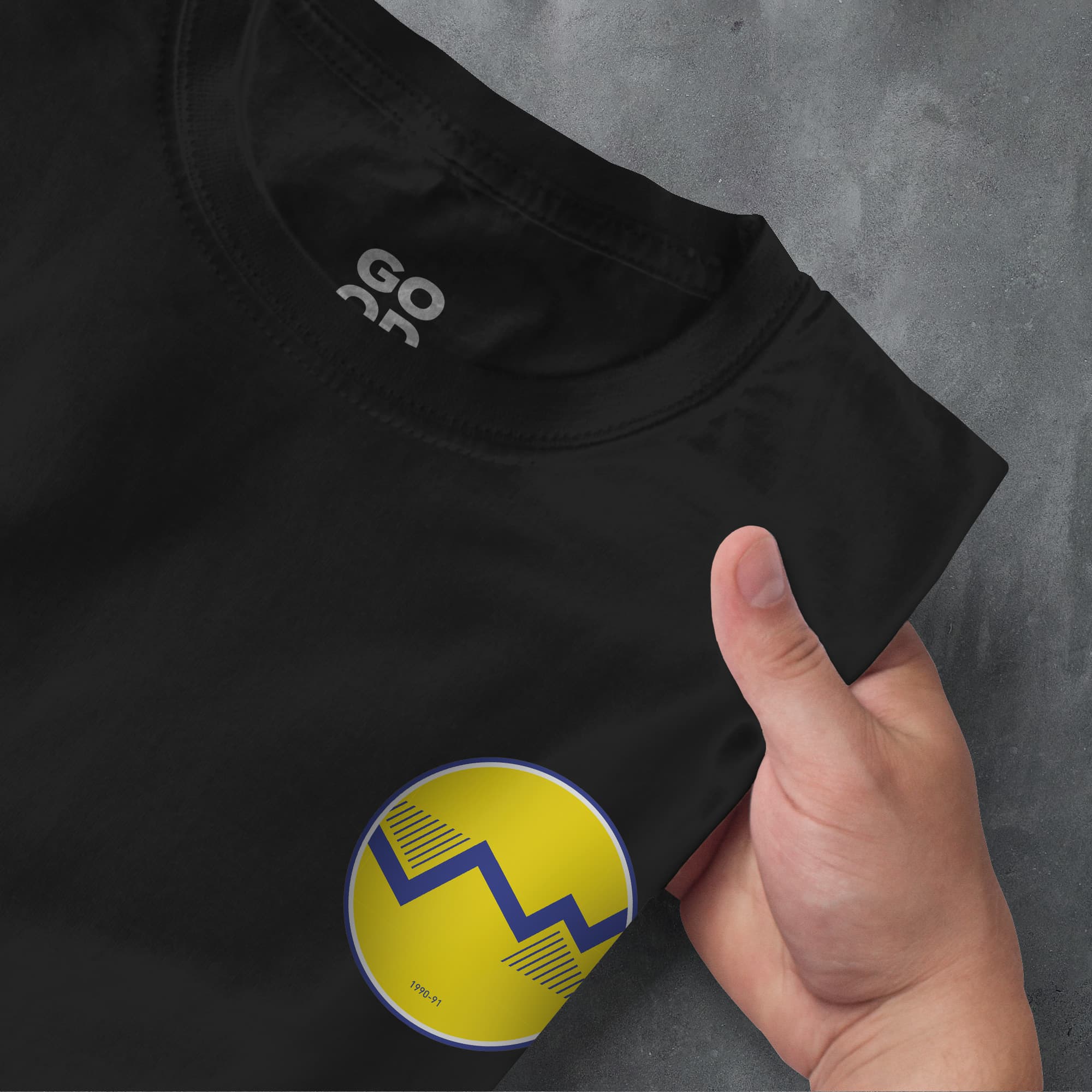 a person pointing at a black shirt with a yellow and blue design on it