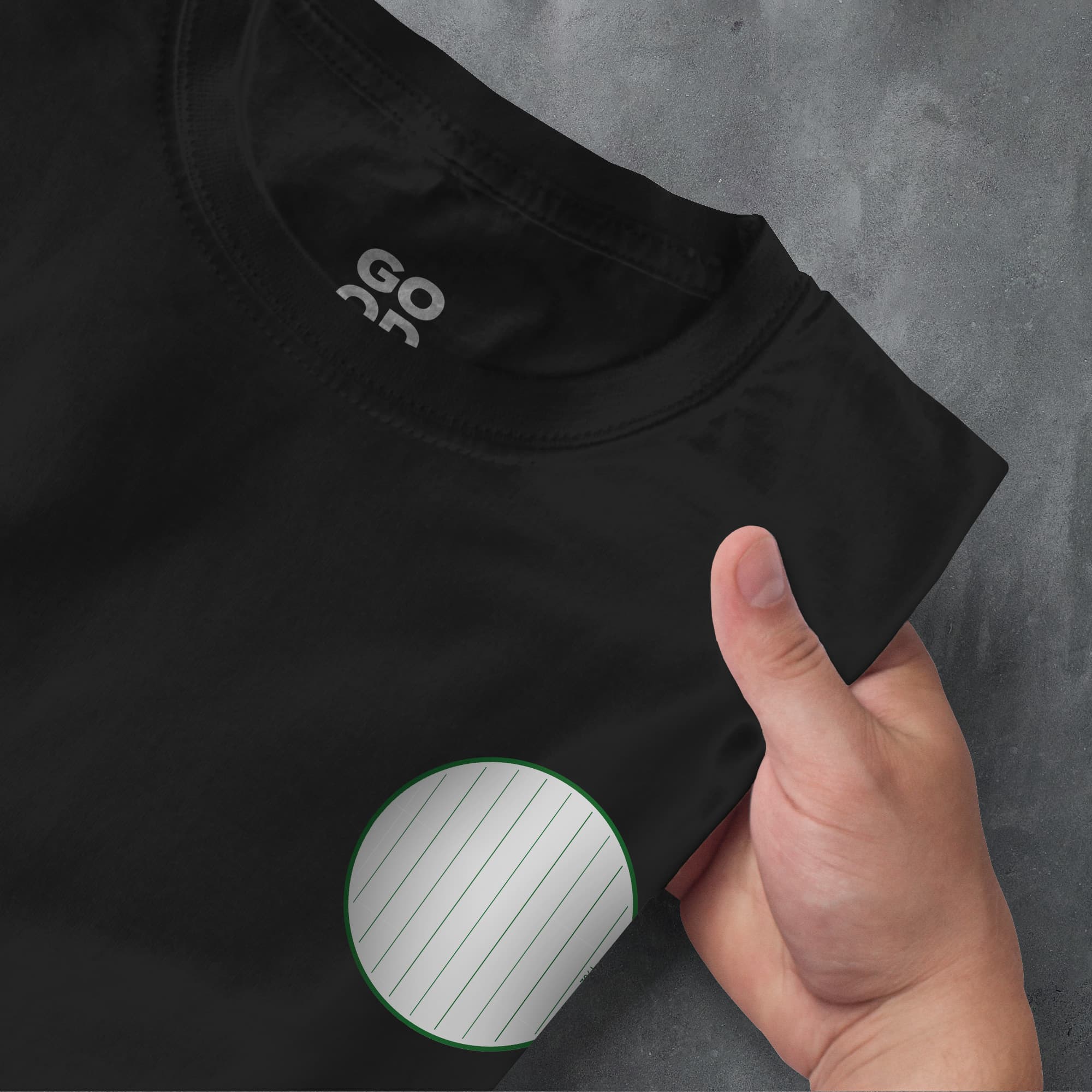 a hand pointing at a black shirt with a green circle on it