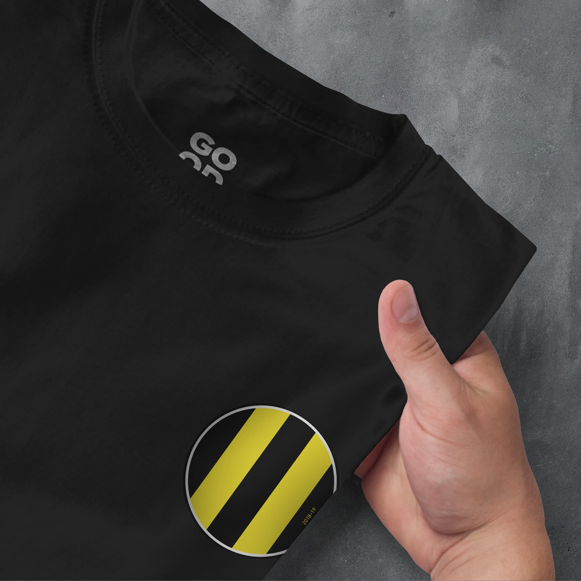 a hand pointing at a black shirt with a yellow stripe