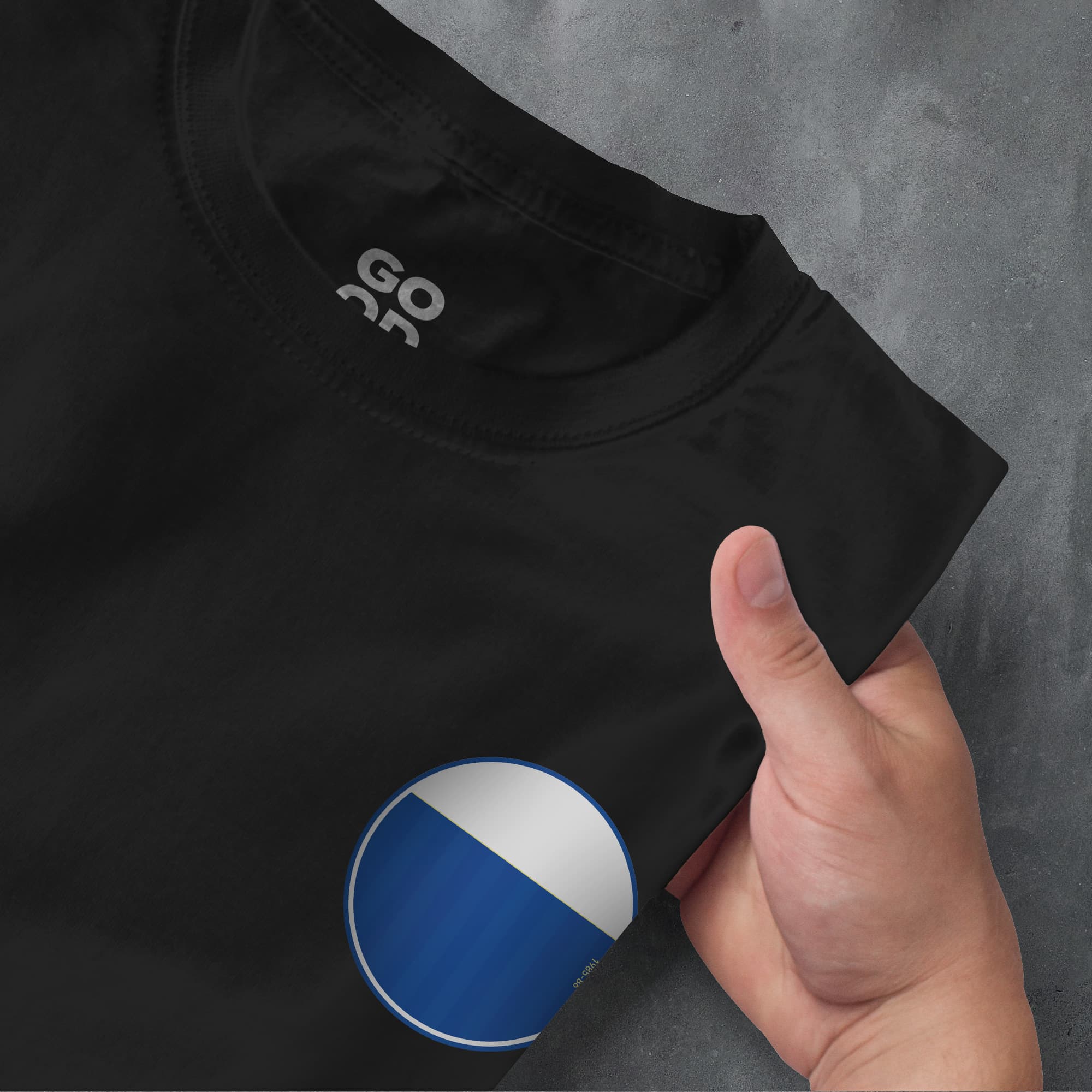 a hand pointing at a black shirt with a blue and white circle on it