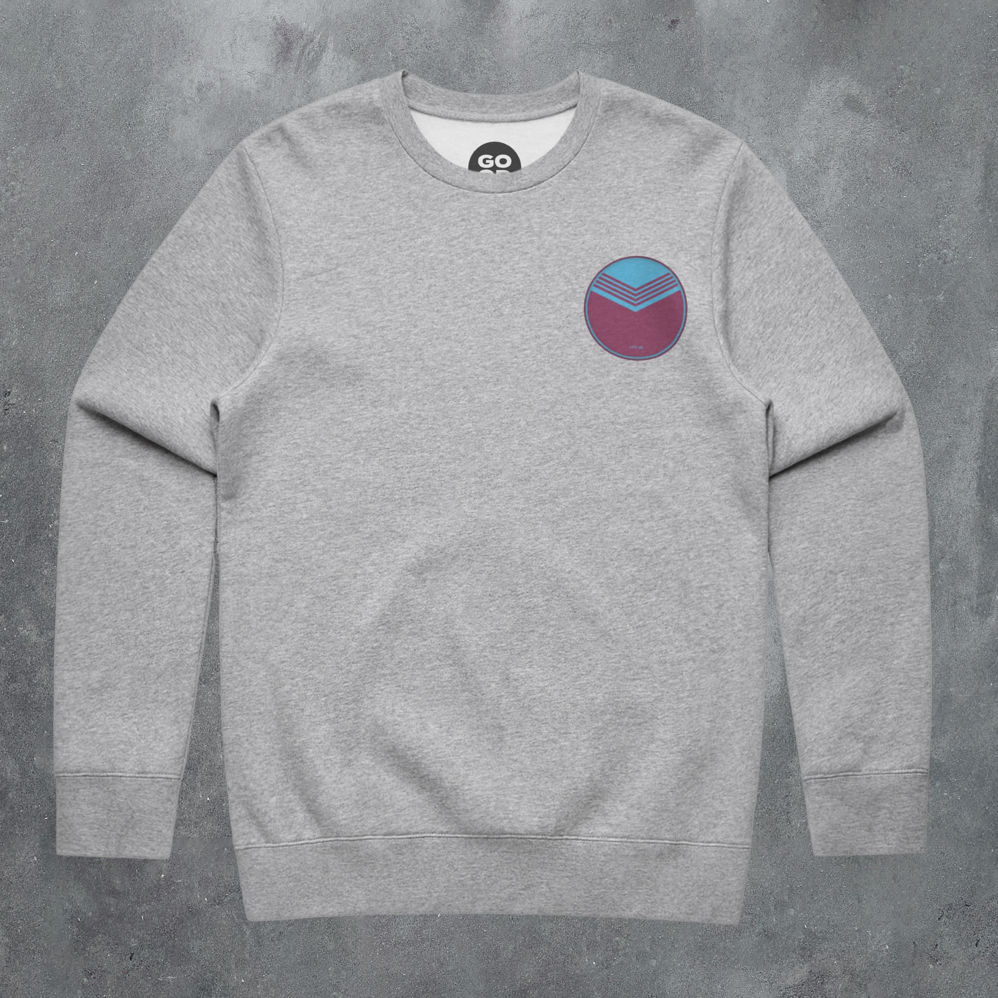 a grey sweatshirt with a blue and red patch on the chest