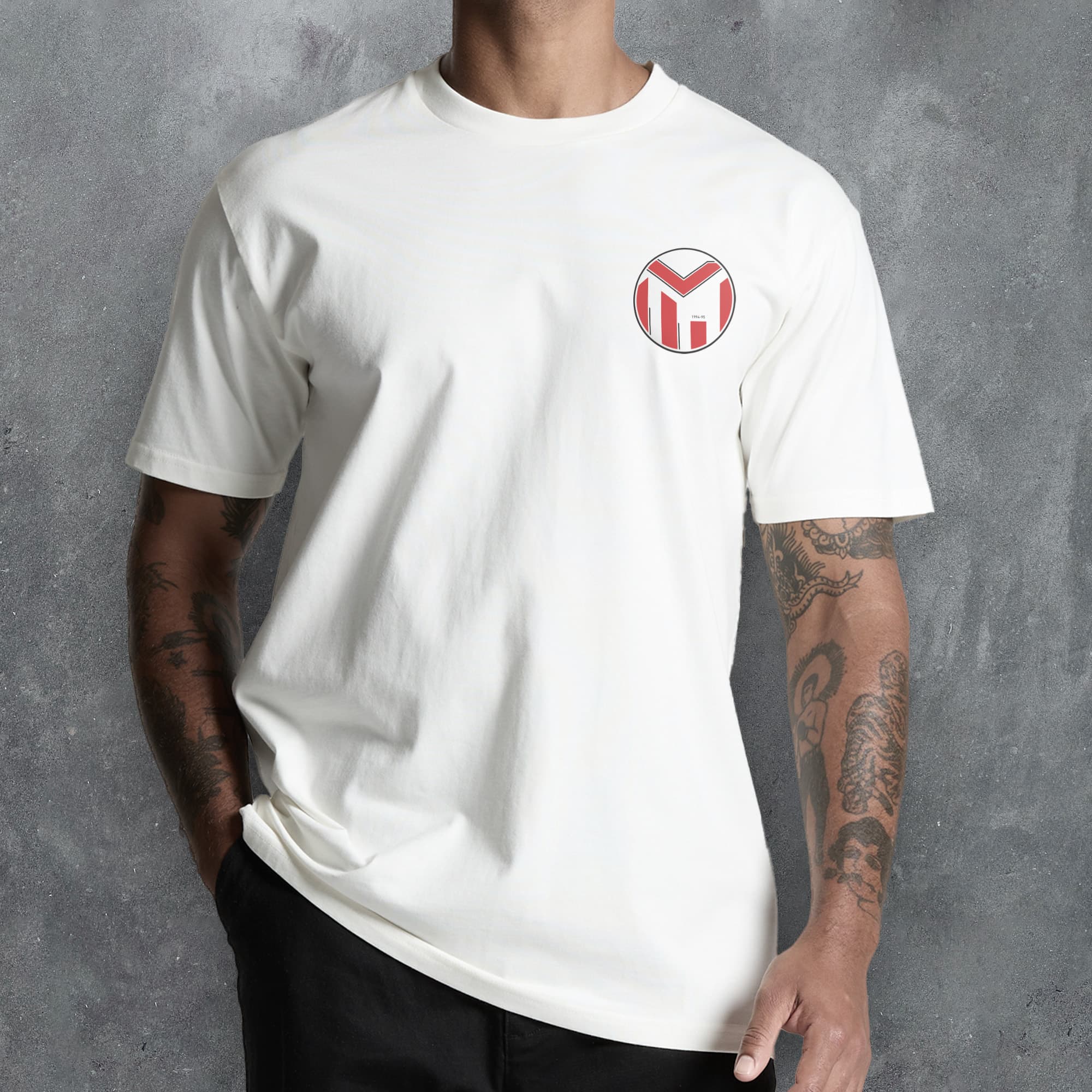 a man wearing a white t - shirt with a red m on it