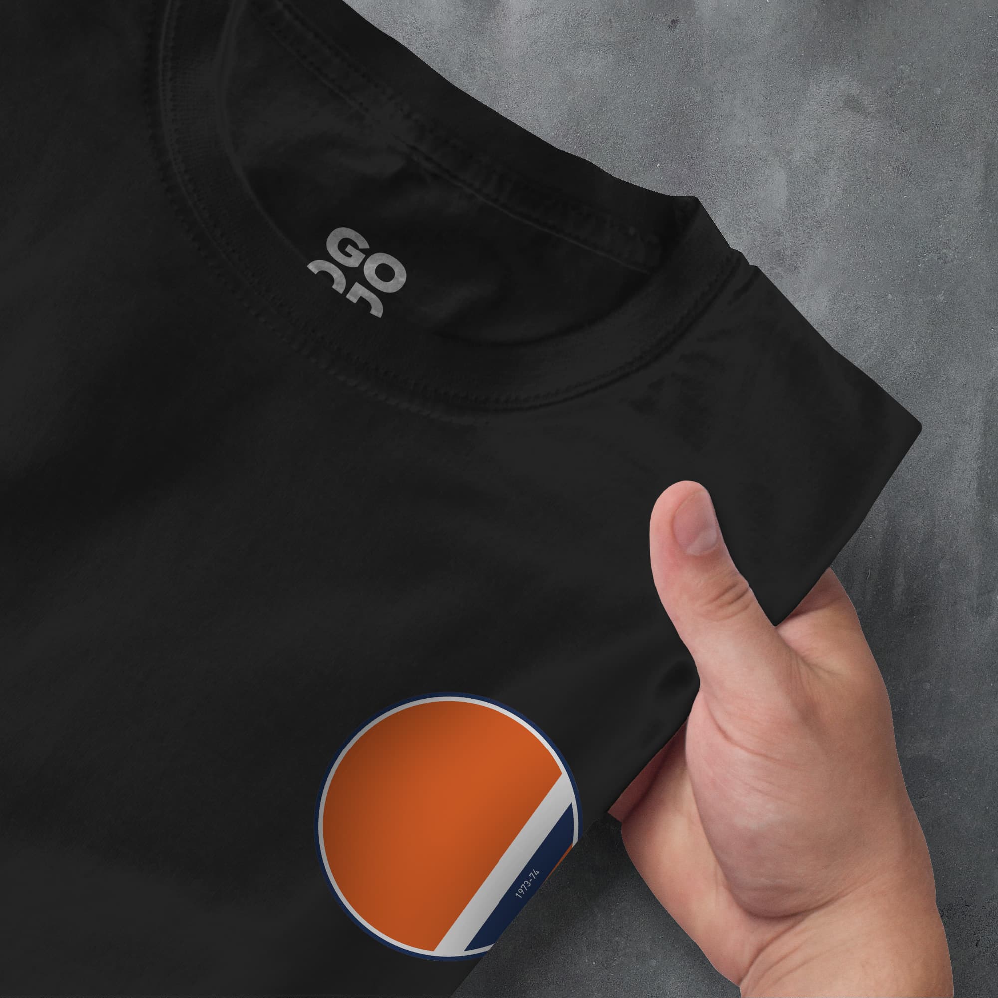 a person pointing at a black shirt with an orange and white circle on it