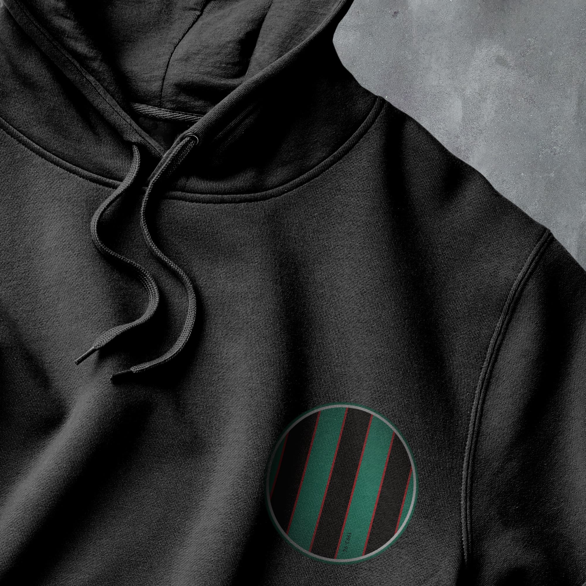 a close up of a black hoodie with a green circle on it