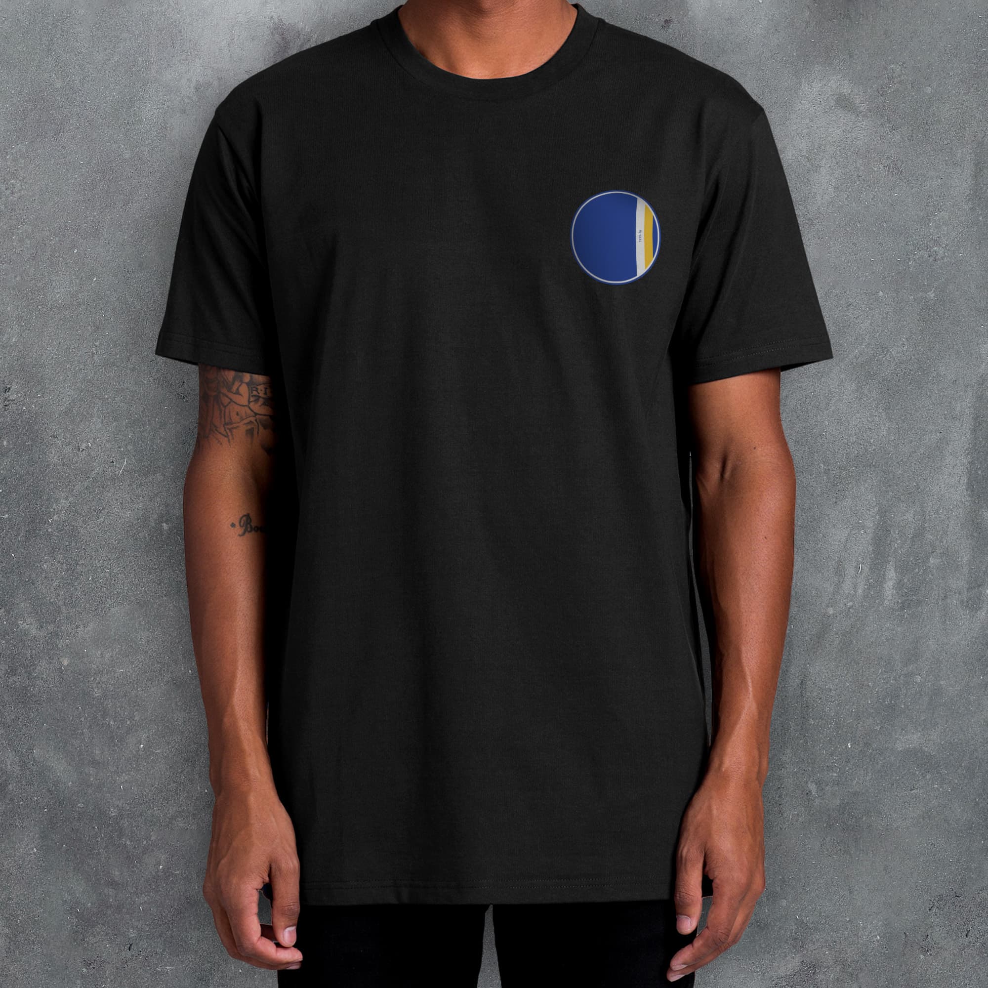 a man wearing a black t - shirt with a blue and yellow circle on the