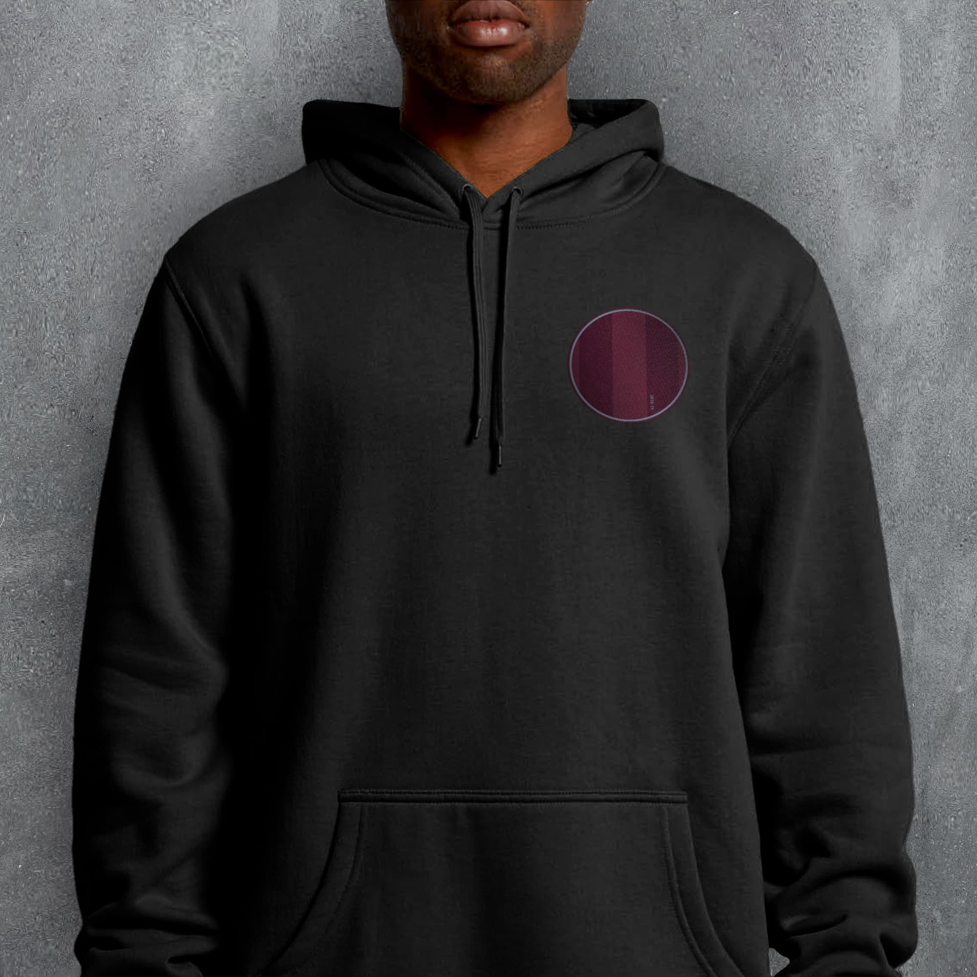 a man wearing a black hoodie with a maroon circle on it