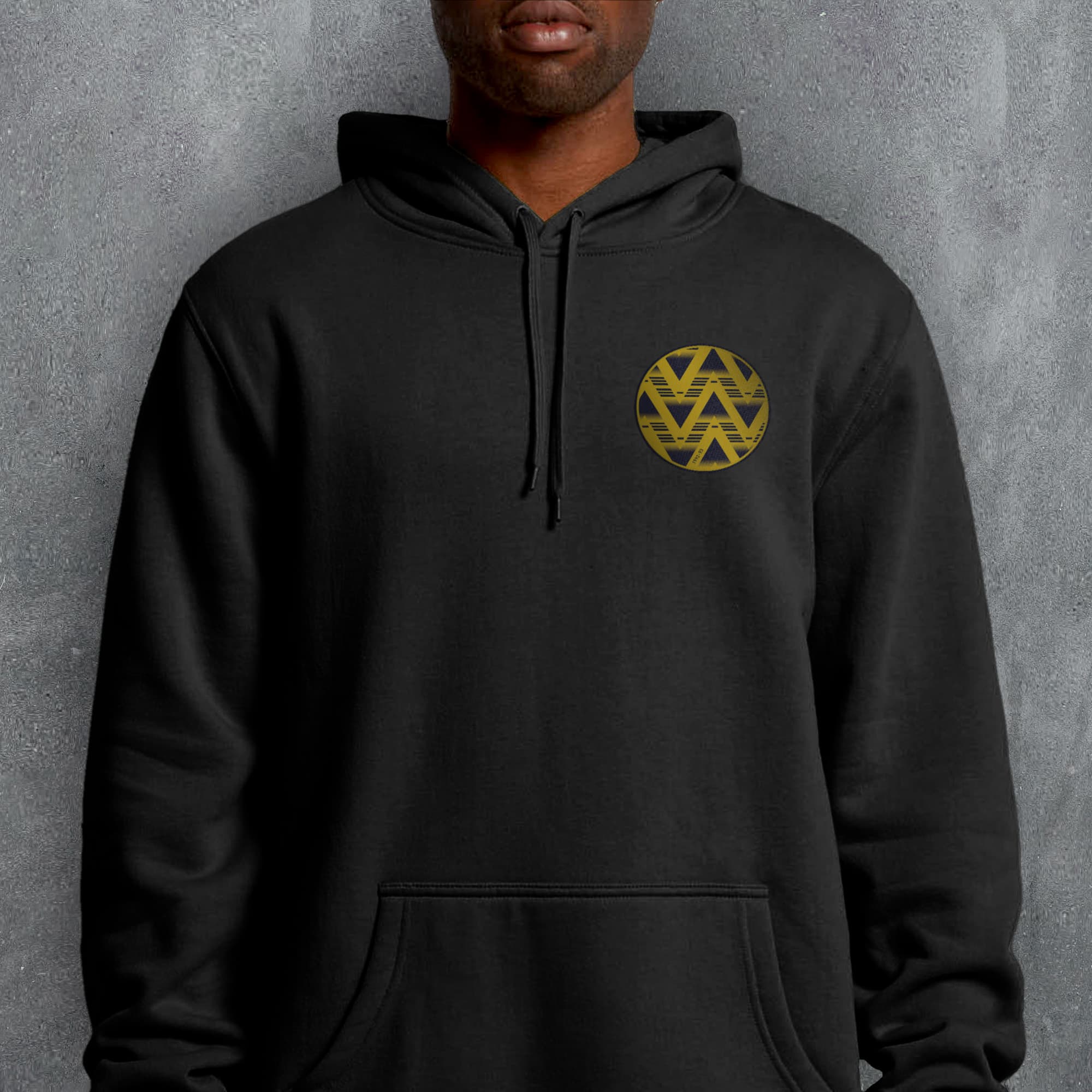 a man wearing a black hoodie with a gold logo