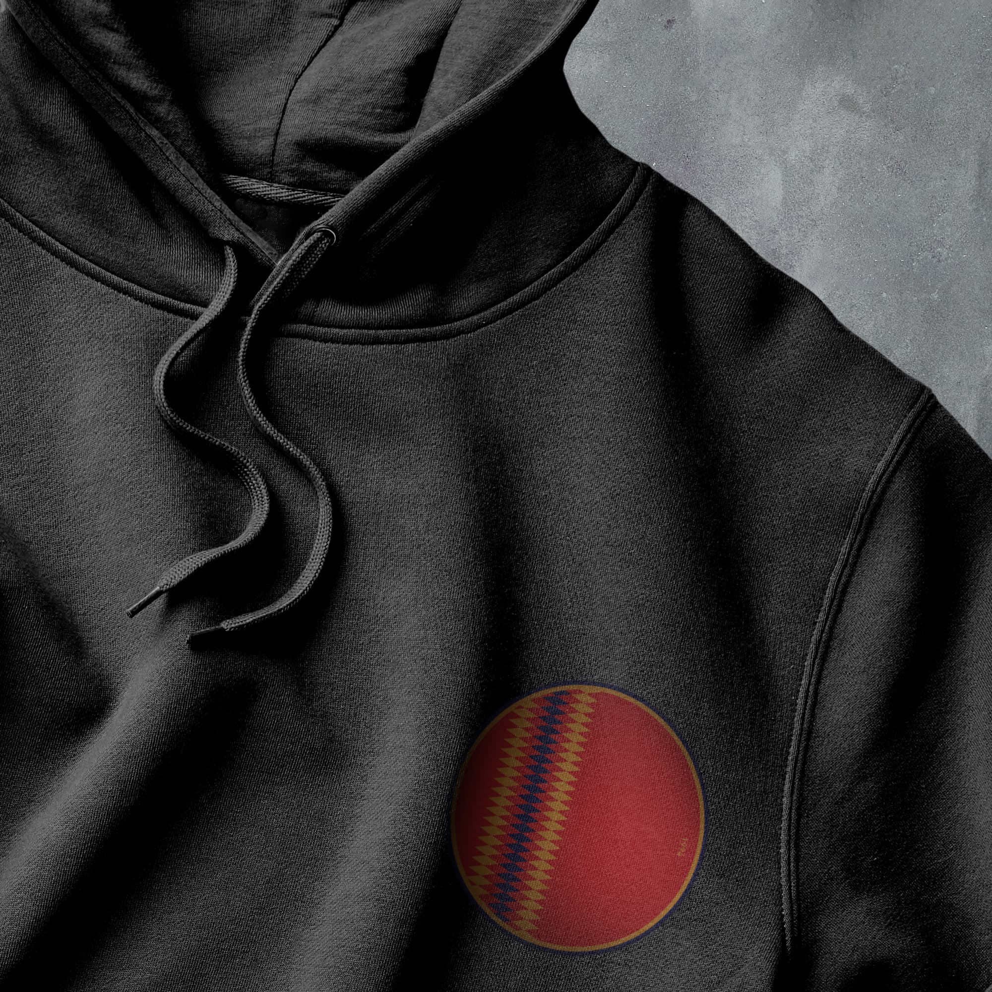 a close up of a black hoodie with a red ball on it