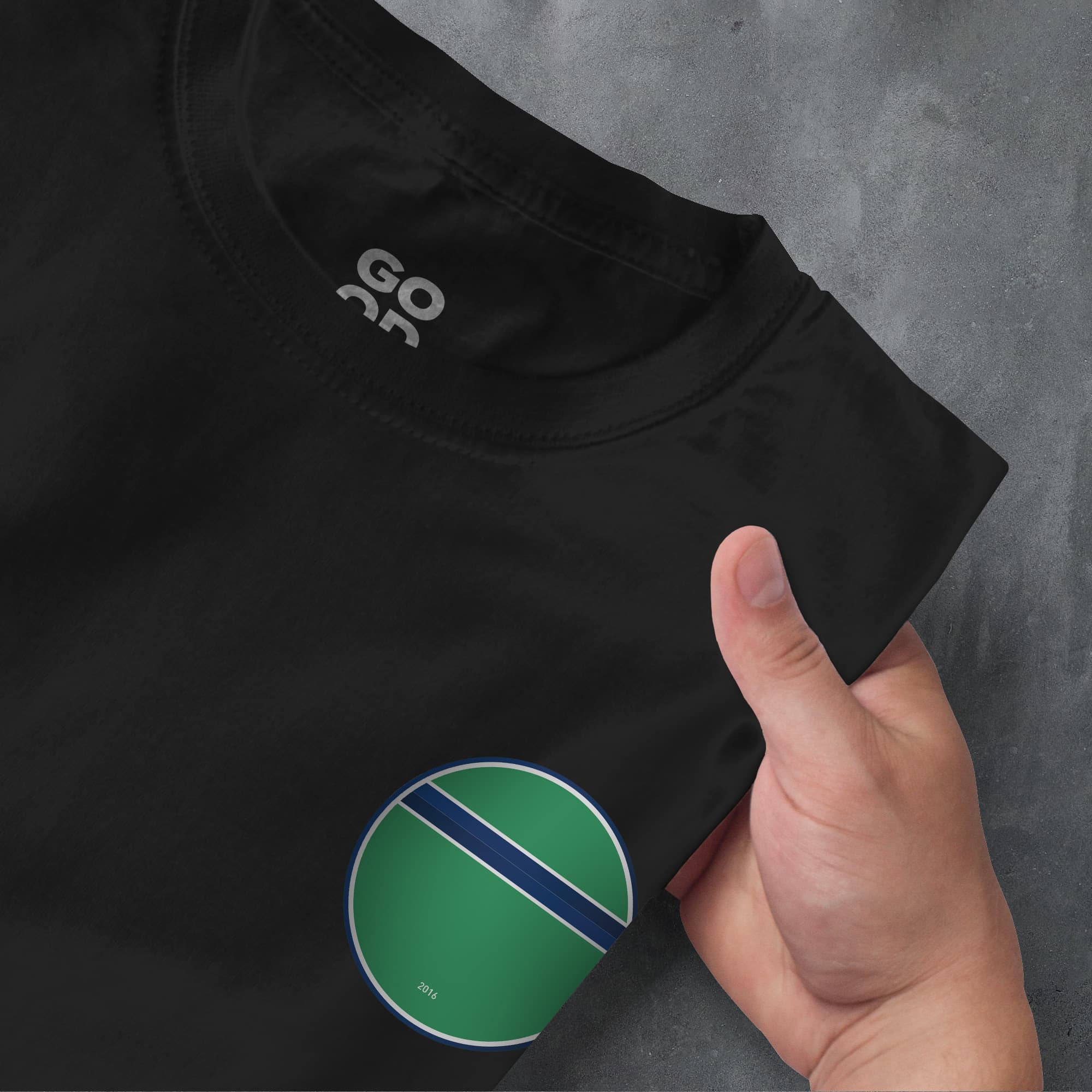 a person's hand pointing at a black shirt with a green and blue stripe