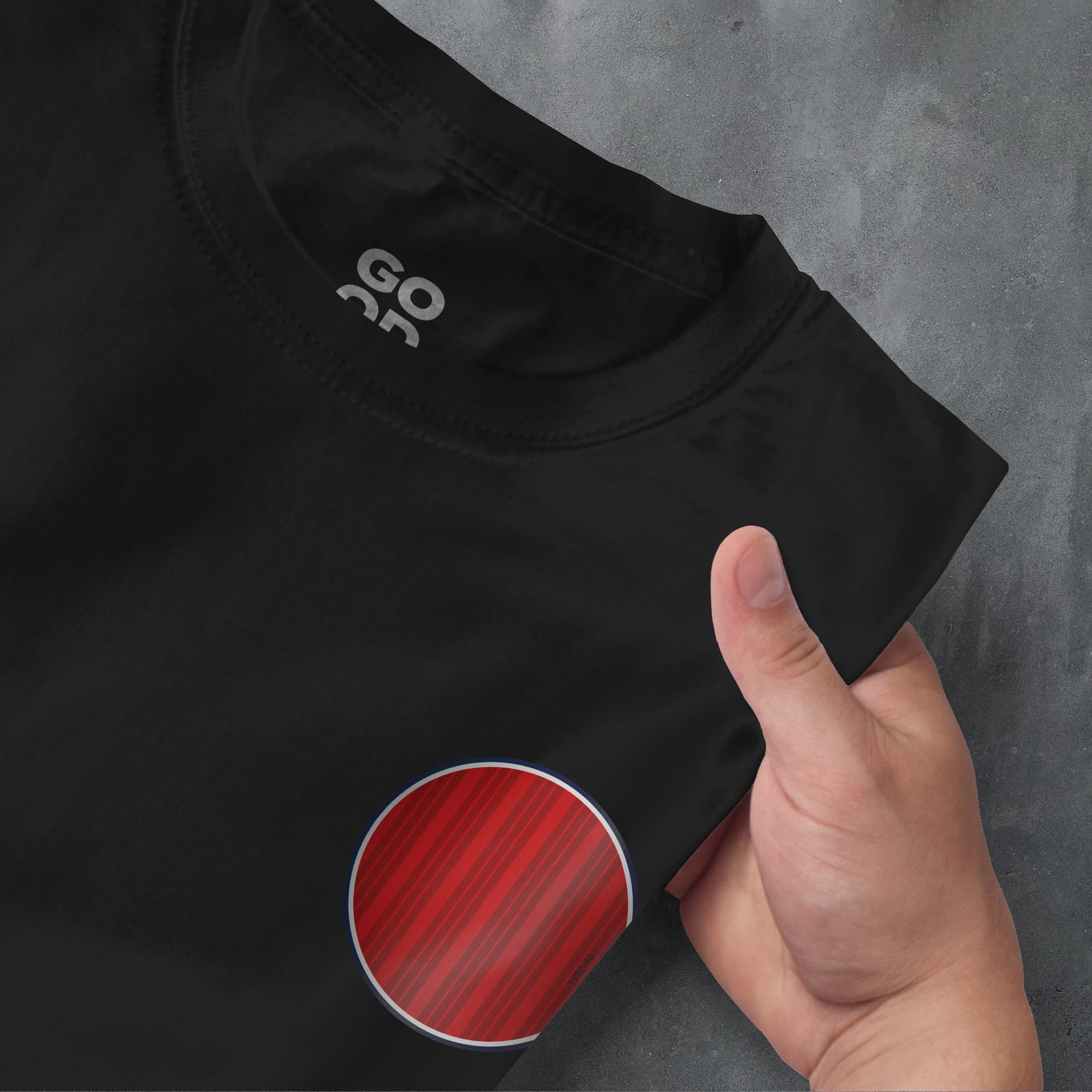 a person pointing at a red circle on a black shirt