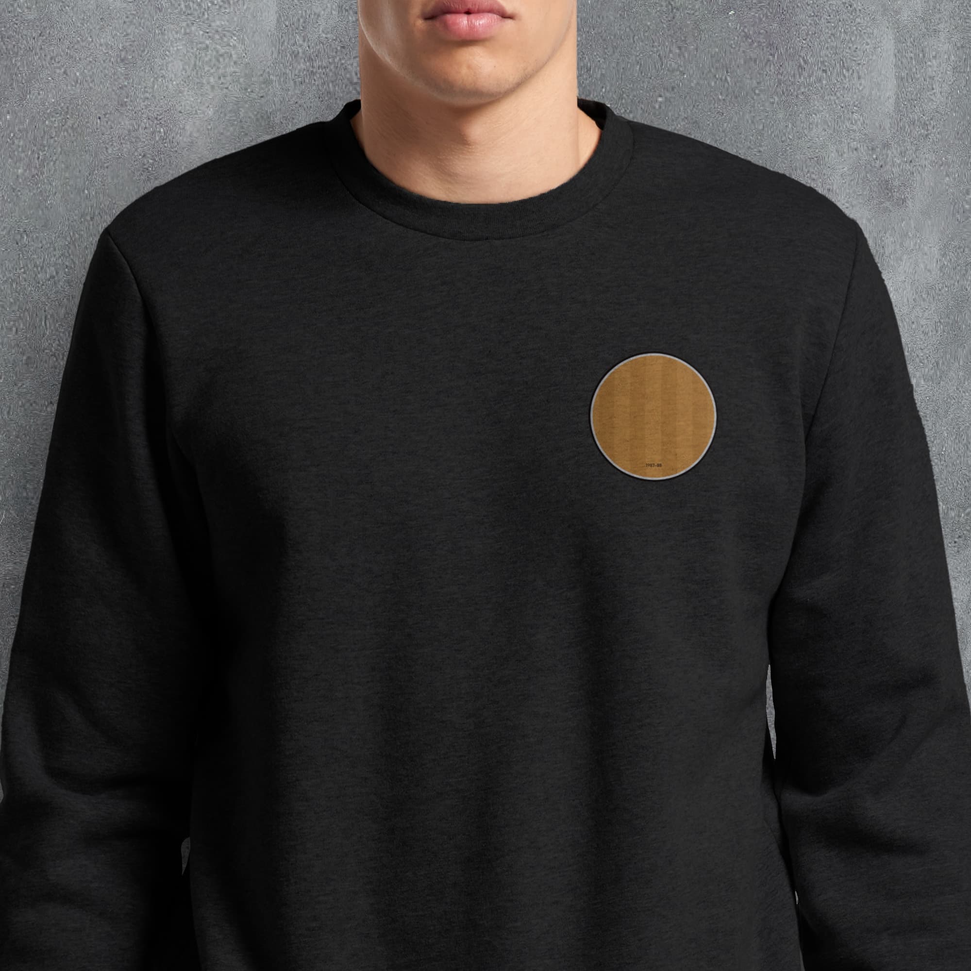 a man wearing a black sweatshirt with a brown circle patch