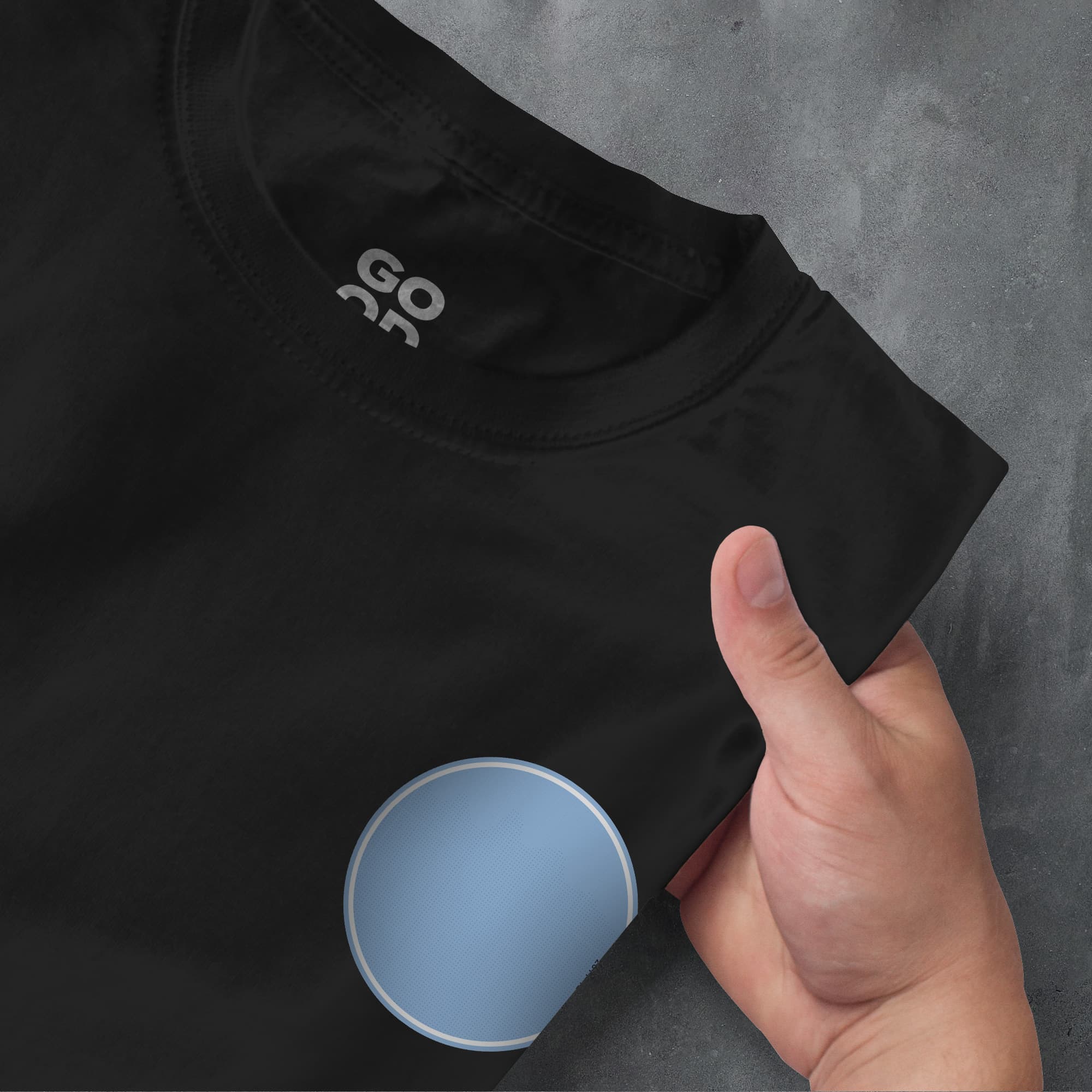 a person's hand pointing at a black t - shirt with the word go