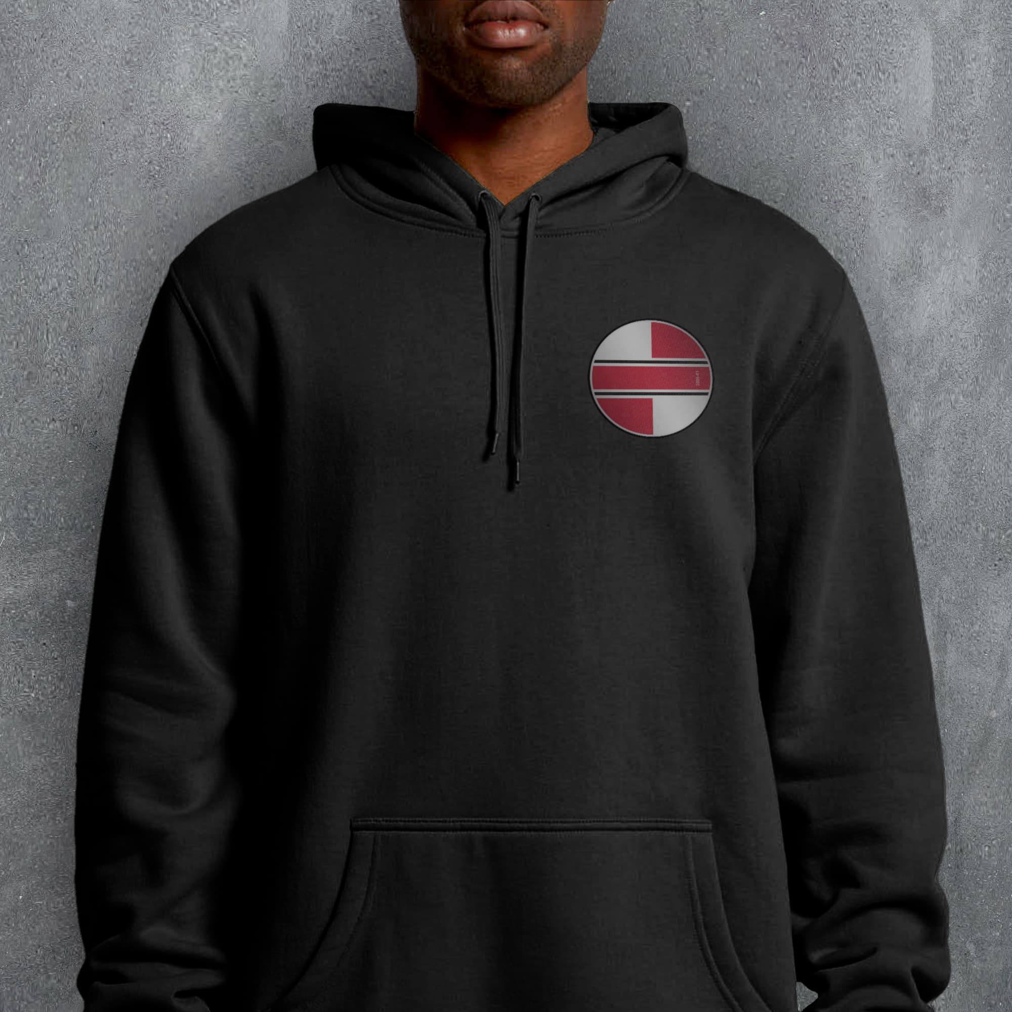 a man wearing a black hoodie with a red cross on it