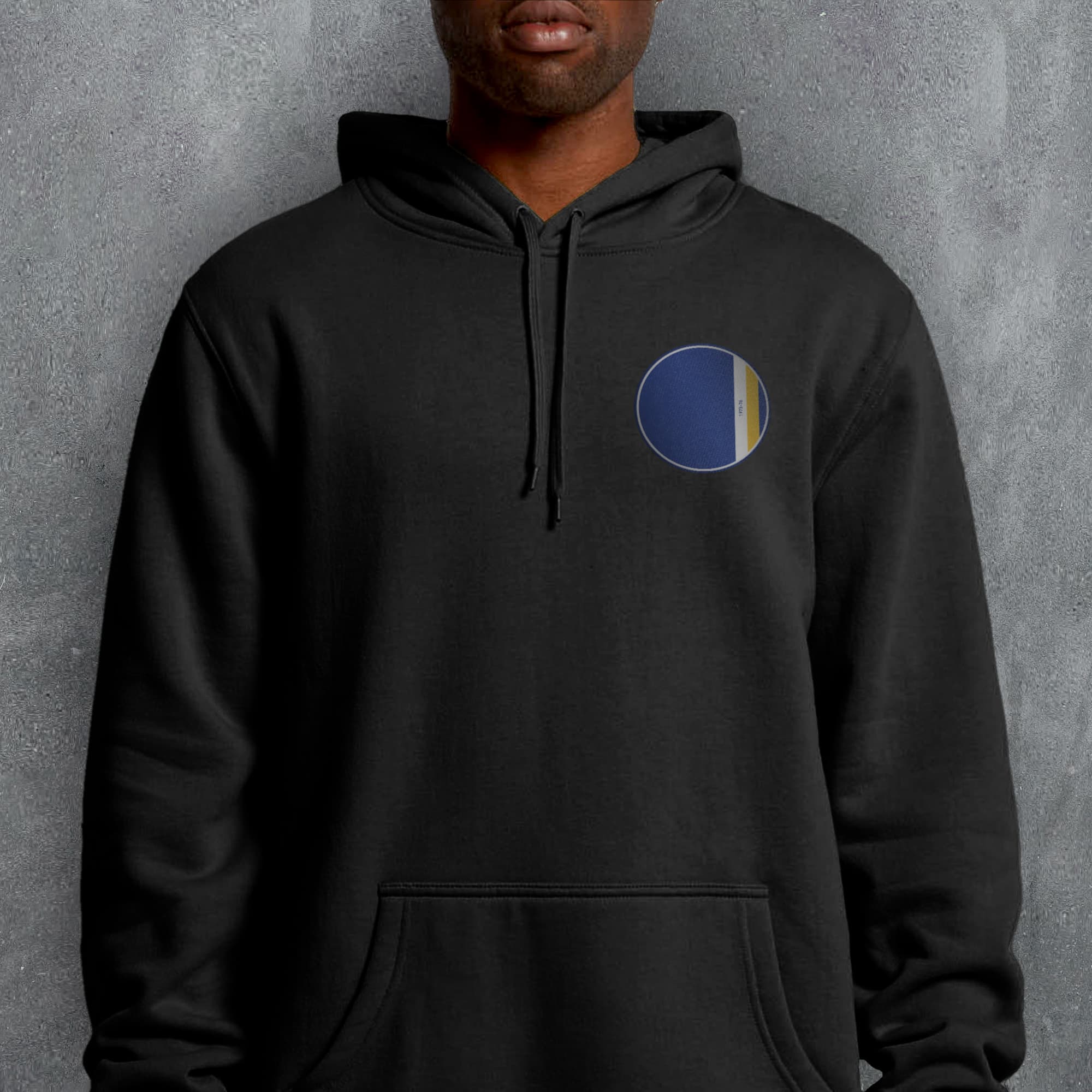 a man wearing a black hoodie with a blue and yellow circle on it