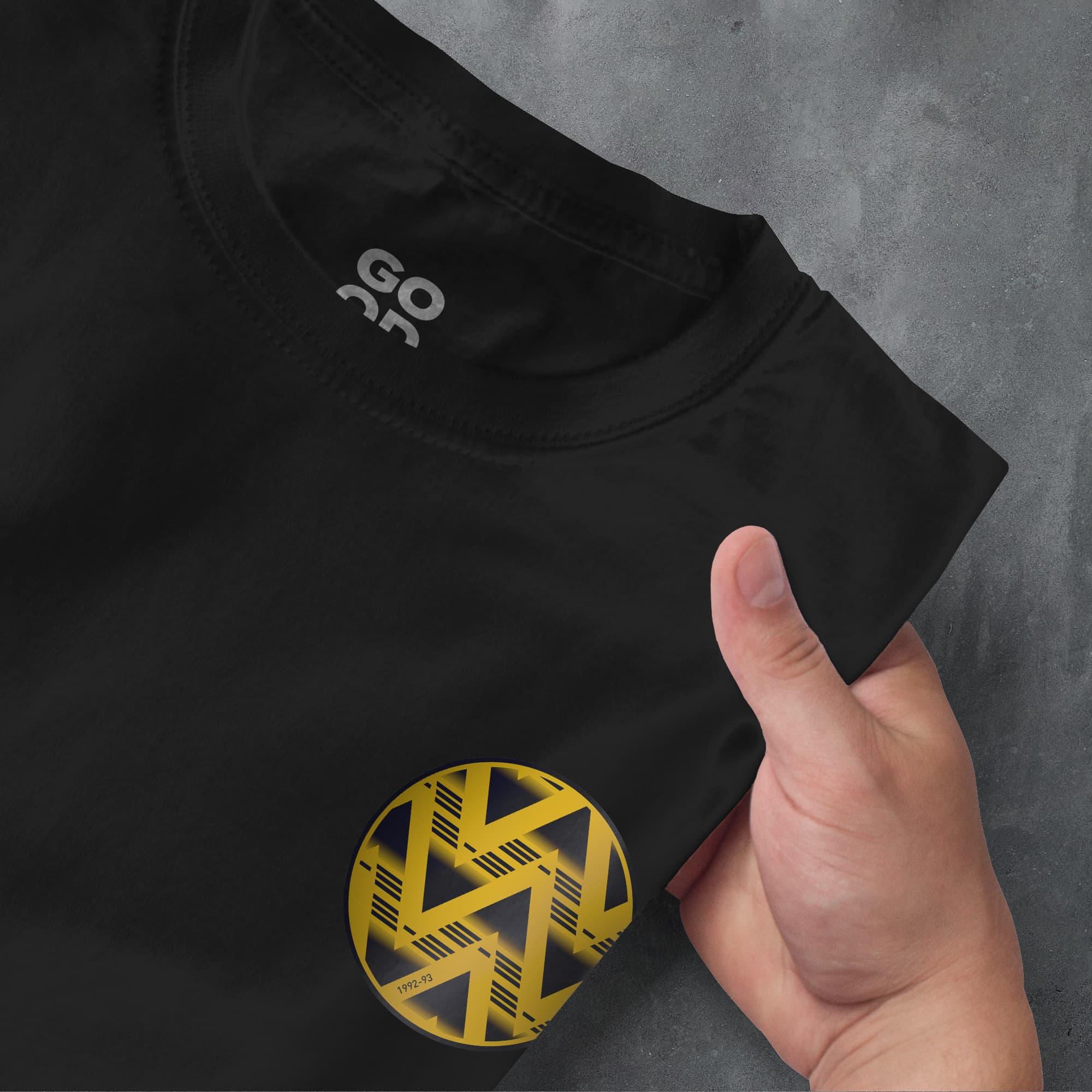 a person holding a black shirt with a yellow logo on it