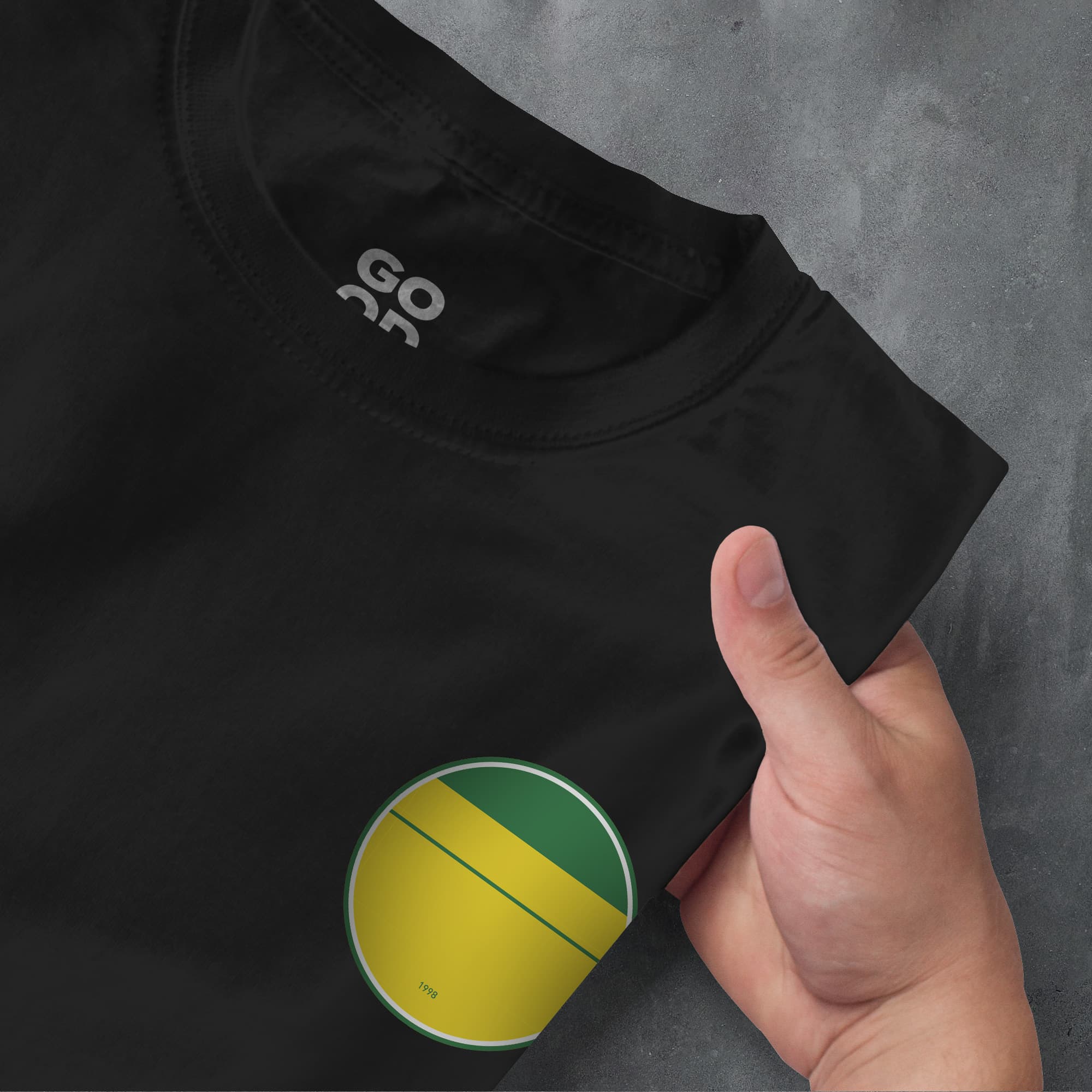 a person's hand pointing at a t - shirt with a green and yellow