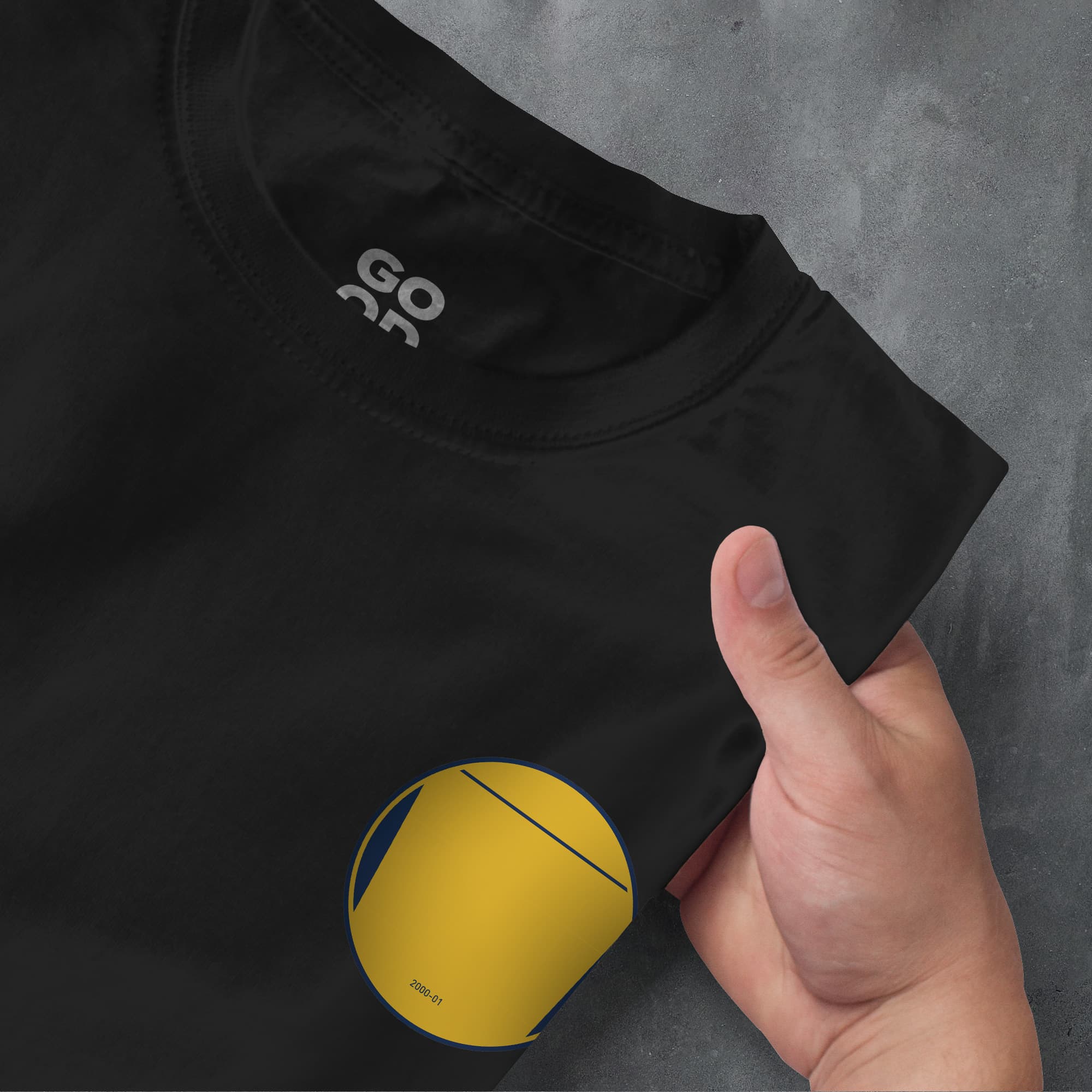 a hand pointing at a t - shirt with a yellow ball on it